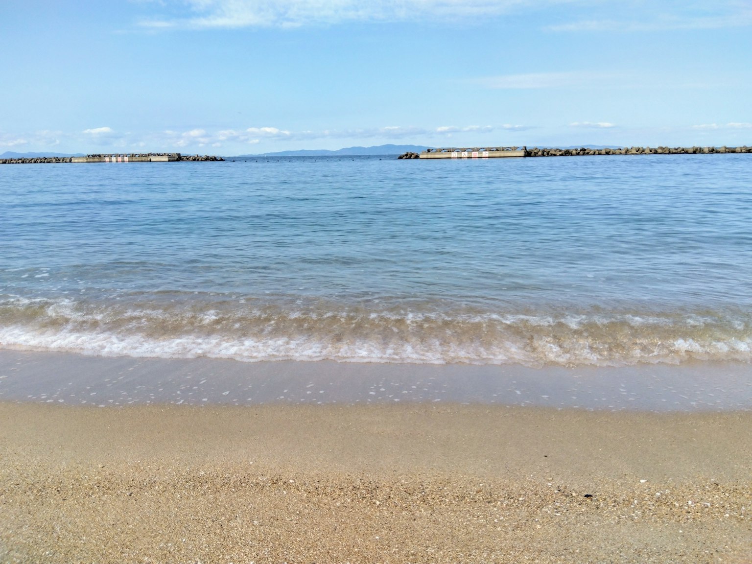 Calm beach scene with blue sky and ocean sandy shore with gentle waves