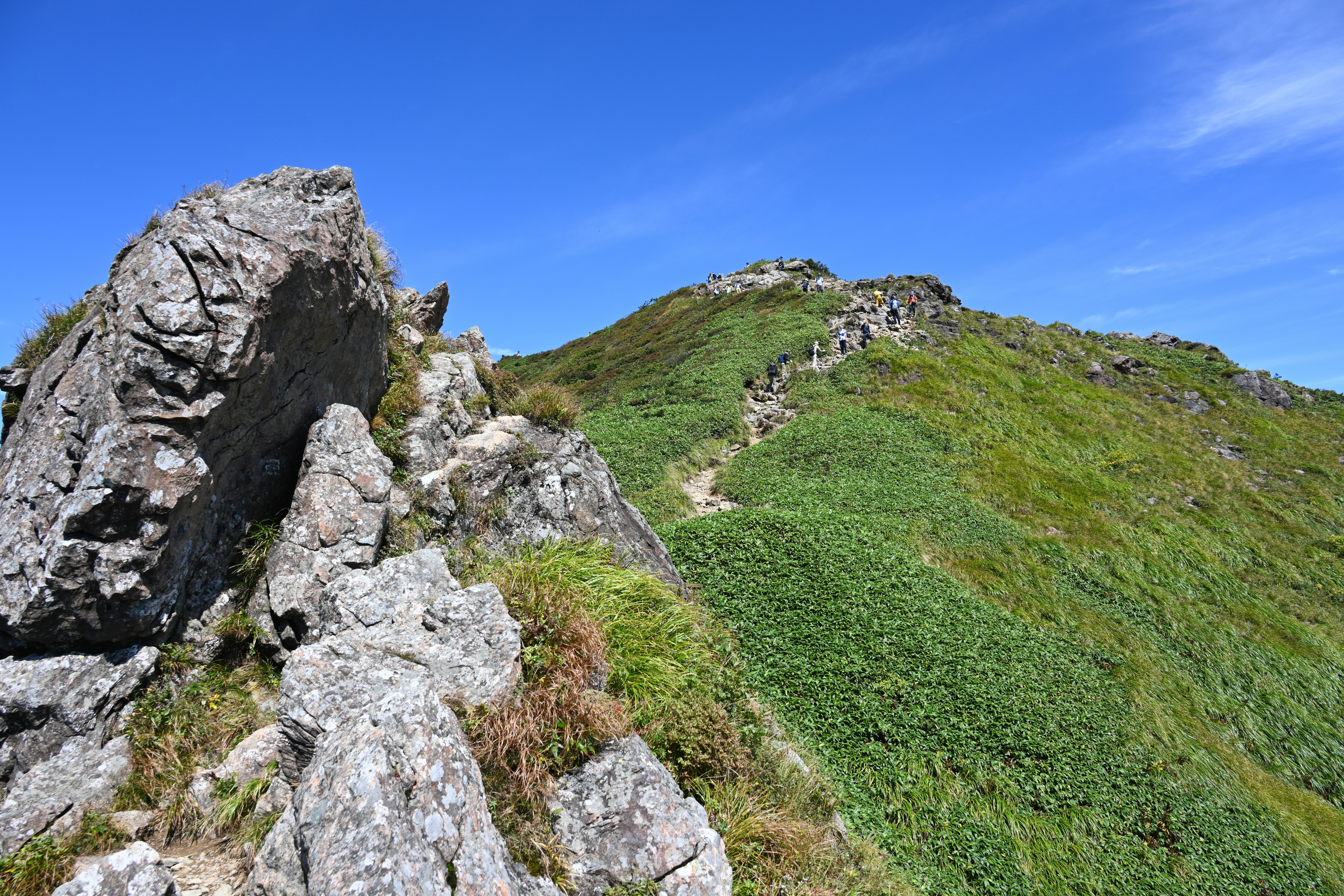 grüner Bergkamm und Wanderweg, vom Felsvorsprung aus gesehen
