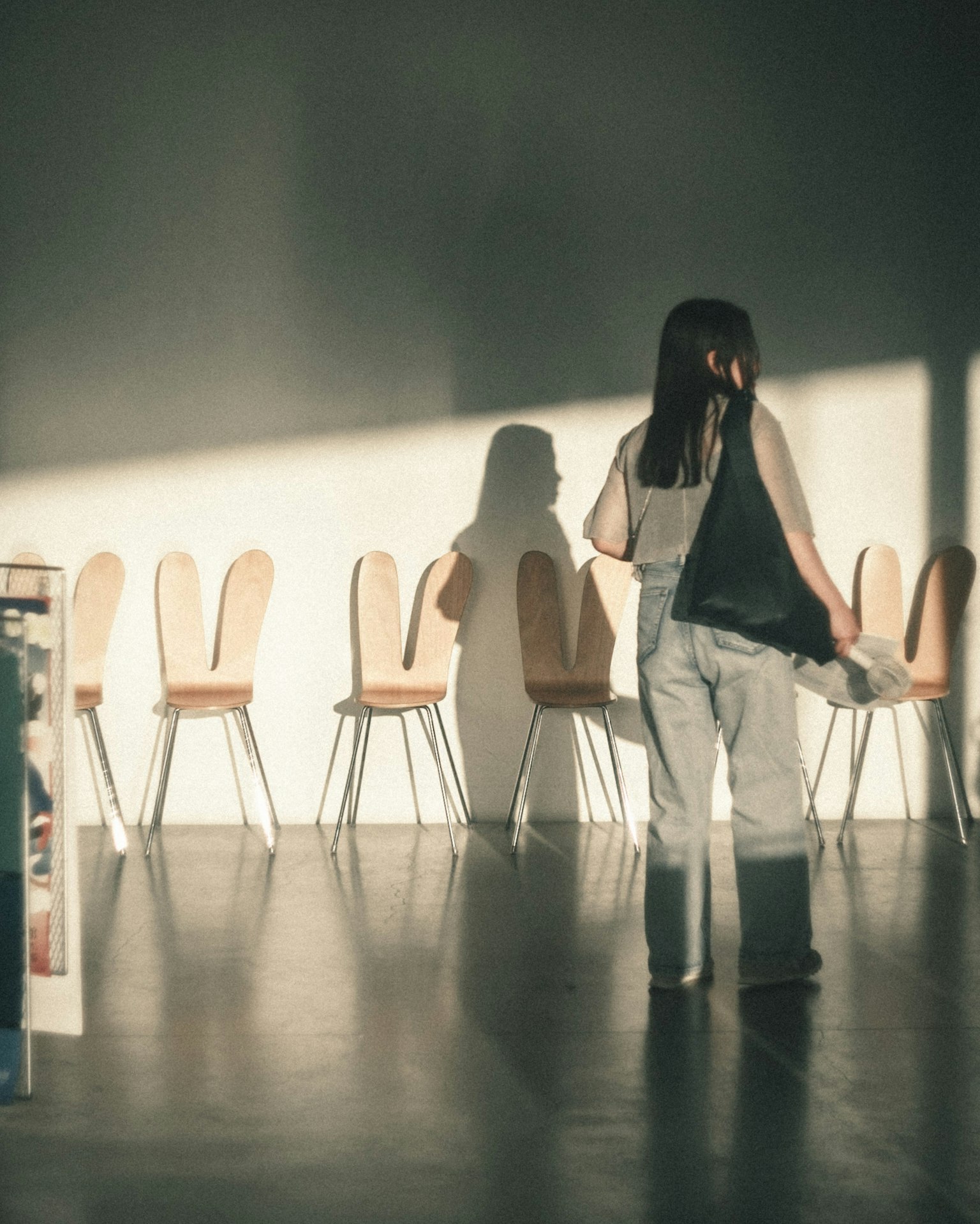 Donna in piedi davanti a sedie che proiettano ombre