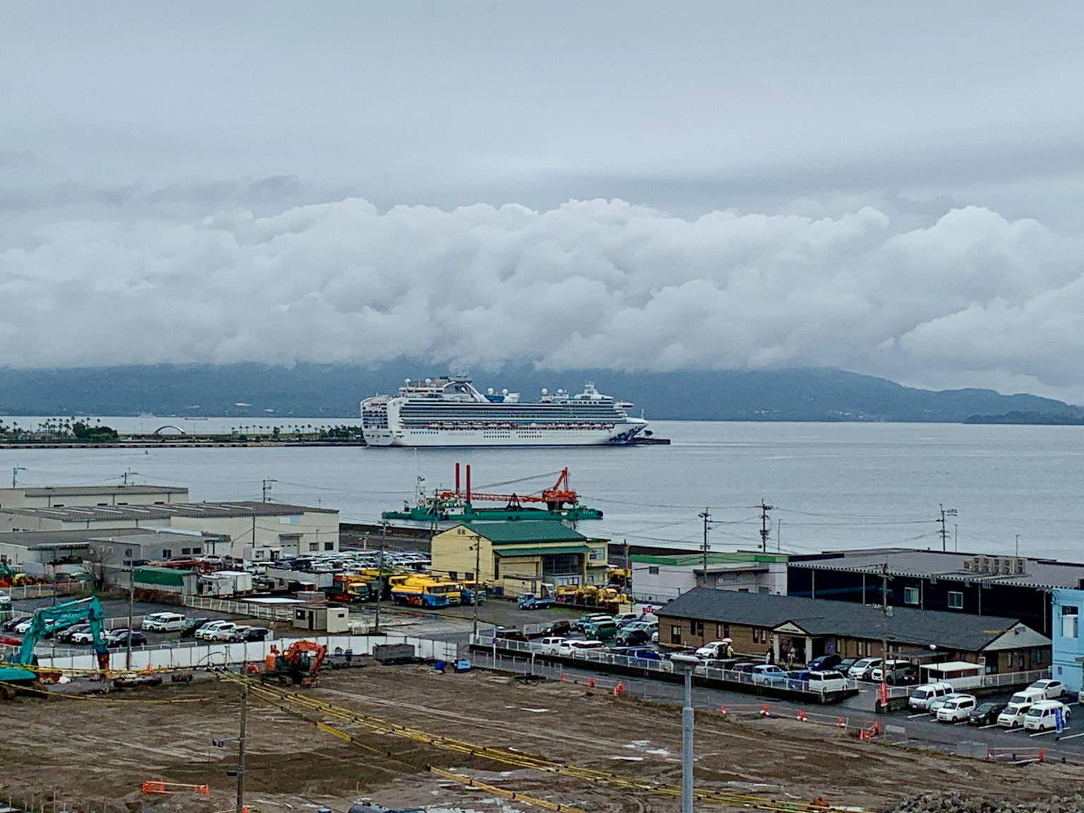 Un navire de croisière amarré dans le port avec des usines et des navires environnants