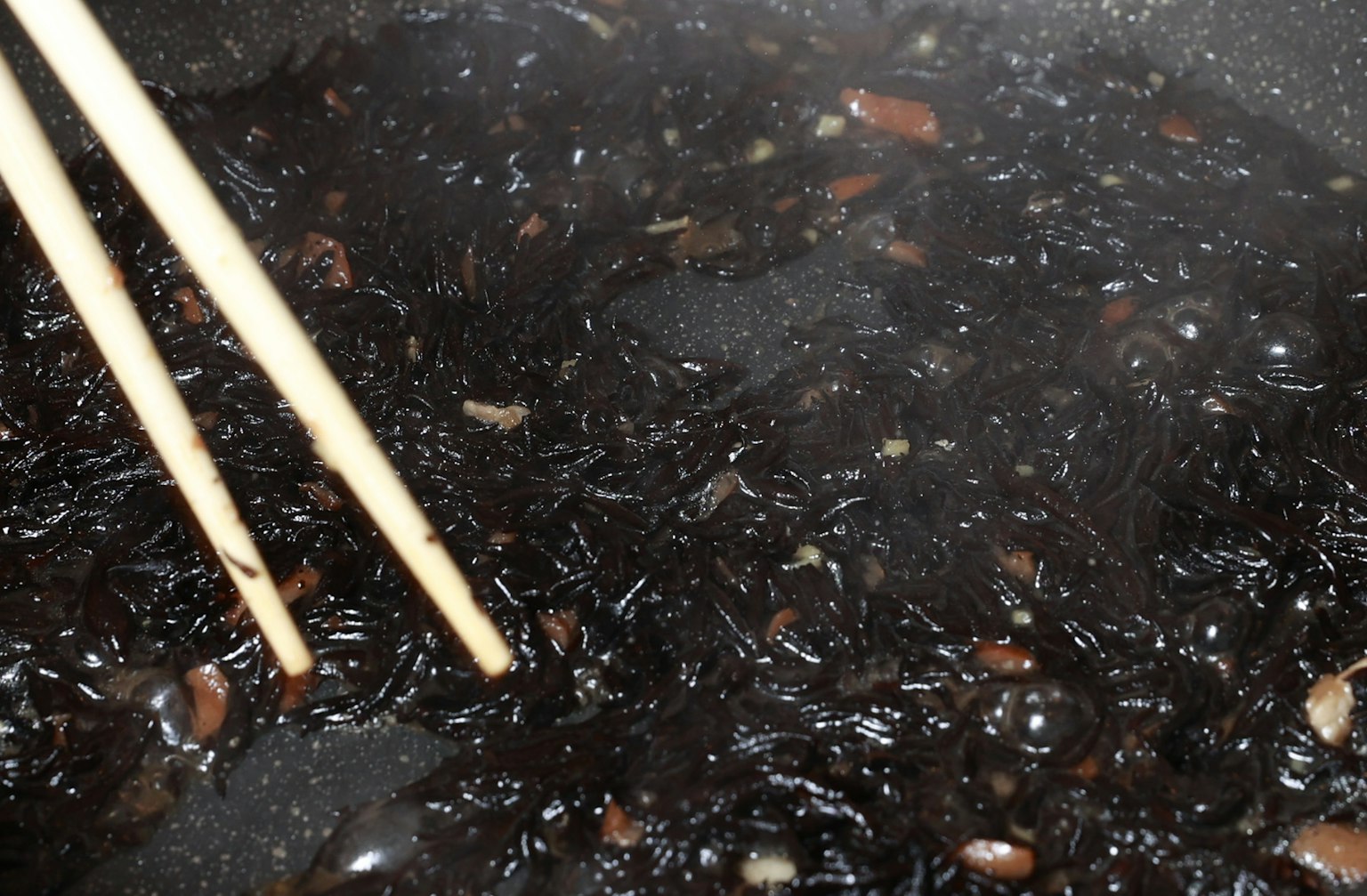 Primo piano di alghe nere in una pentola con bacchette di legno