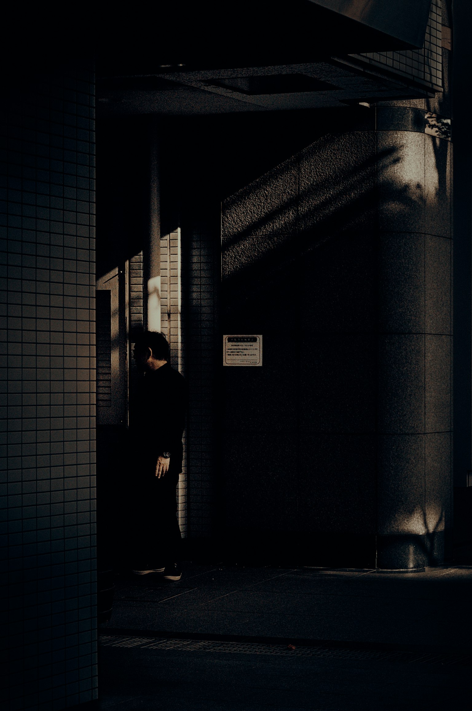 Una figura de pie en un pasillo oscuro con sombras contrastantes