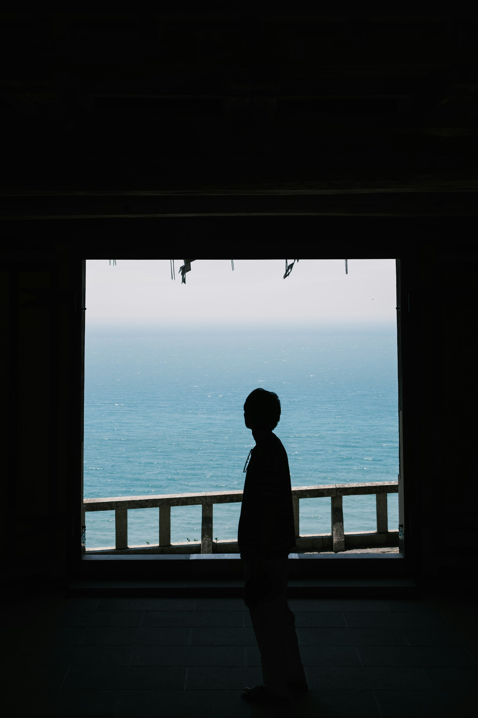 Silhouette của một người đứng trước cửa sổ nhìn ra biển