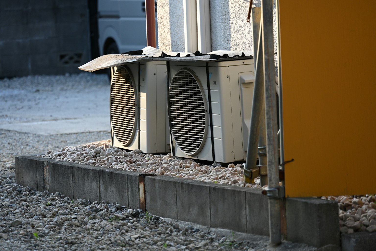 Deux unités de climatisation extérieures à côté d'une surface en gravier