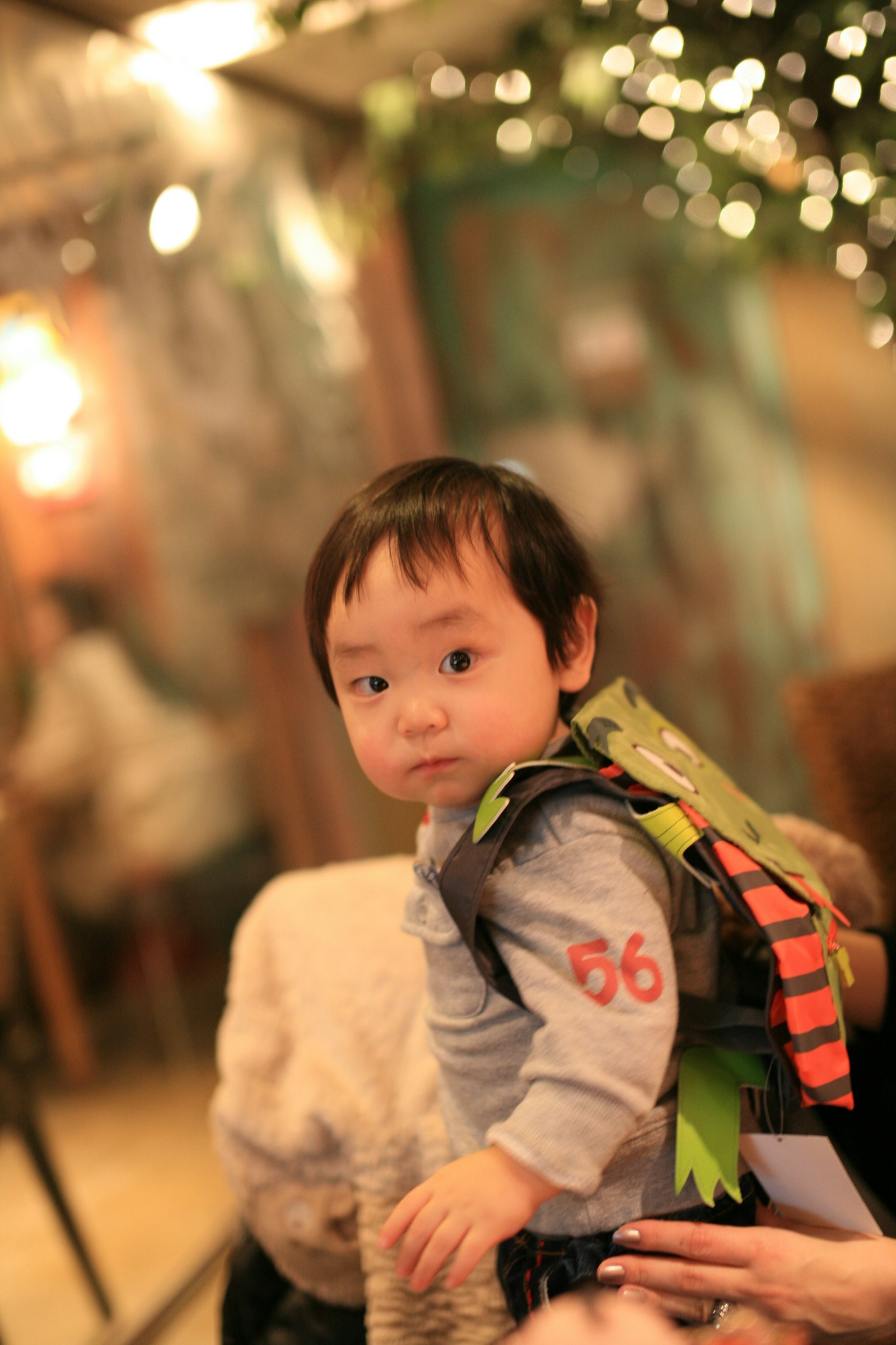 A small child wearing a colorful backpack with a playful design