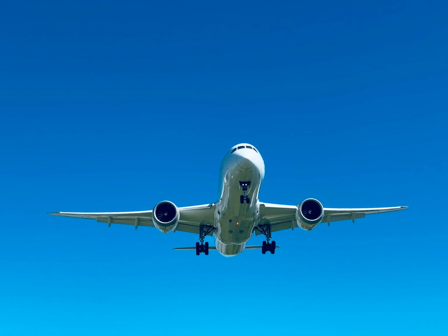 Passenger airplane flying against a clear blue sky from a low angle