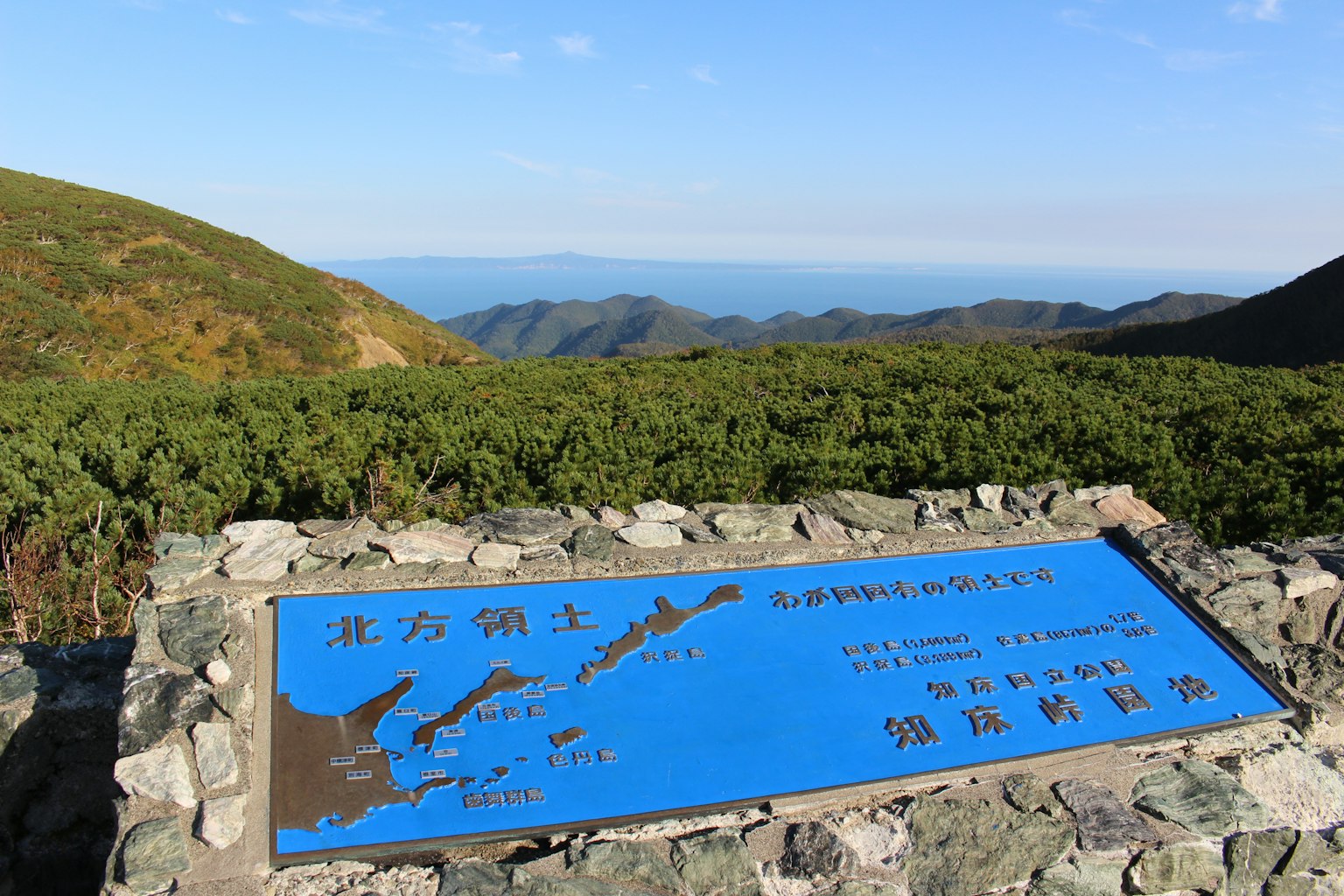 Blue sign in a mountainous landscape with green vegetation and distant views