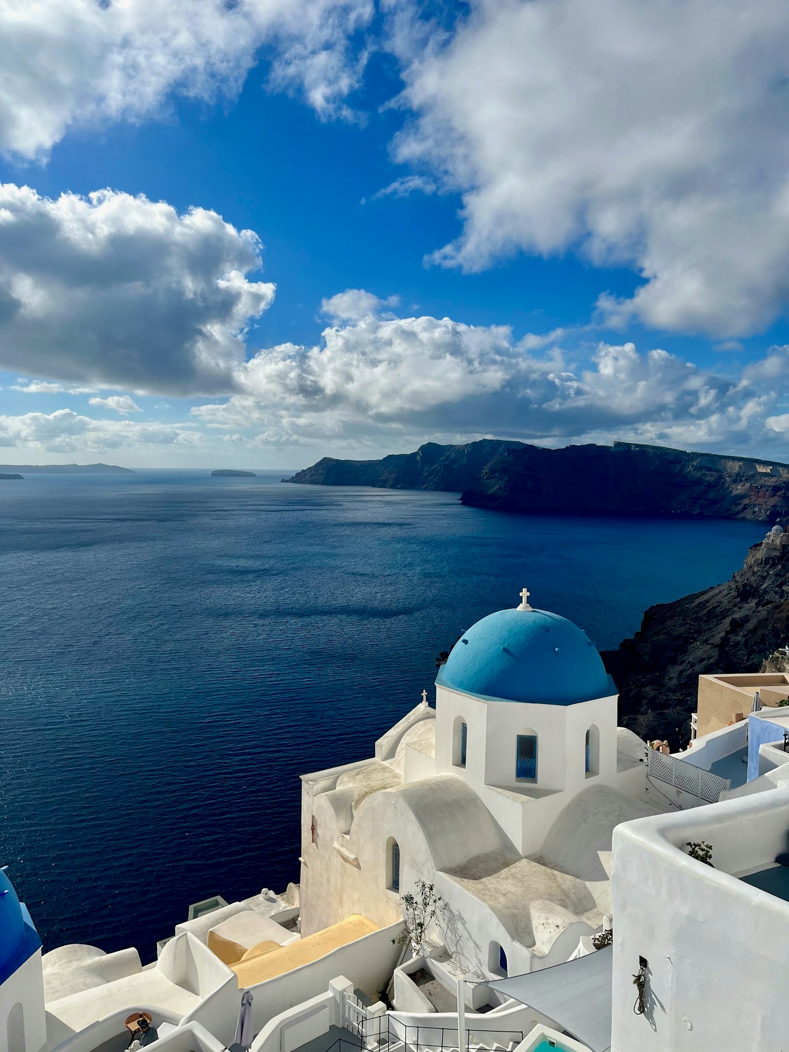 Eine atemberaubende Aussicht auf die Ägäis mit einer blau-domigen Kirche in Santorin