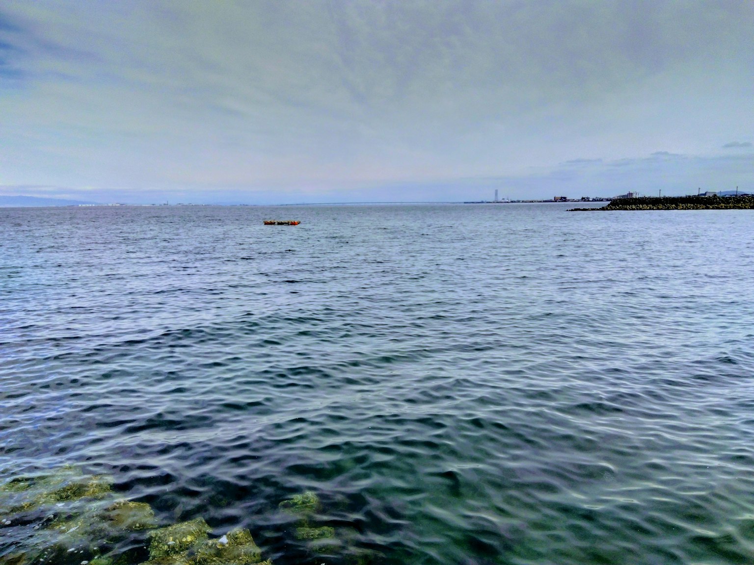 Pemandangan laut dan langit yang tenang perahu kecil mengapung cahaya yang memantul di air
