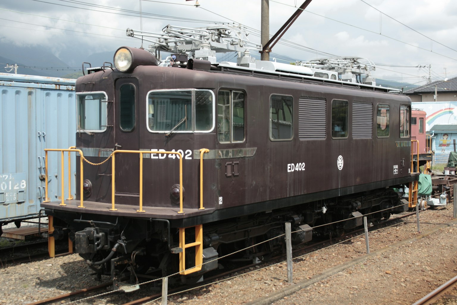 Locomotora eléctrica marrón ED102 estacionada en una estación