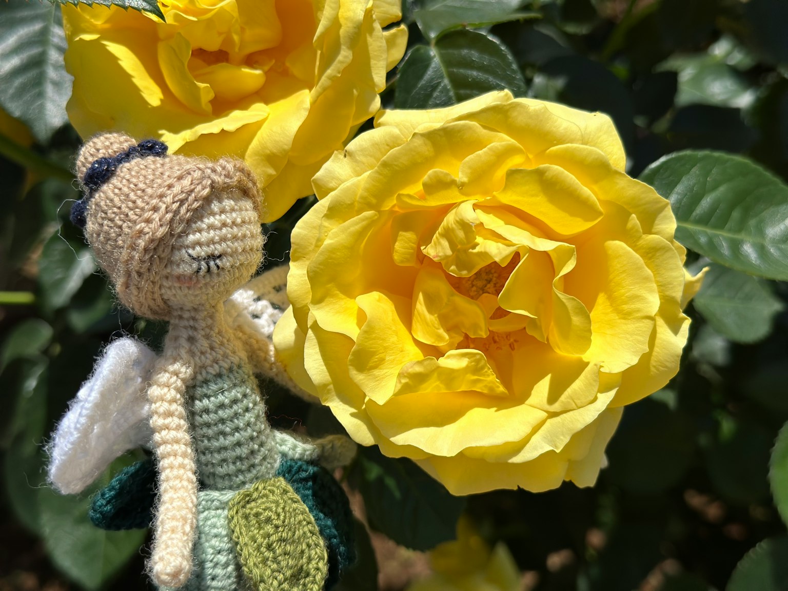 Fata all'uncinetto accanto a una rosa gialla