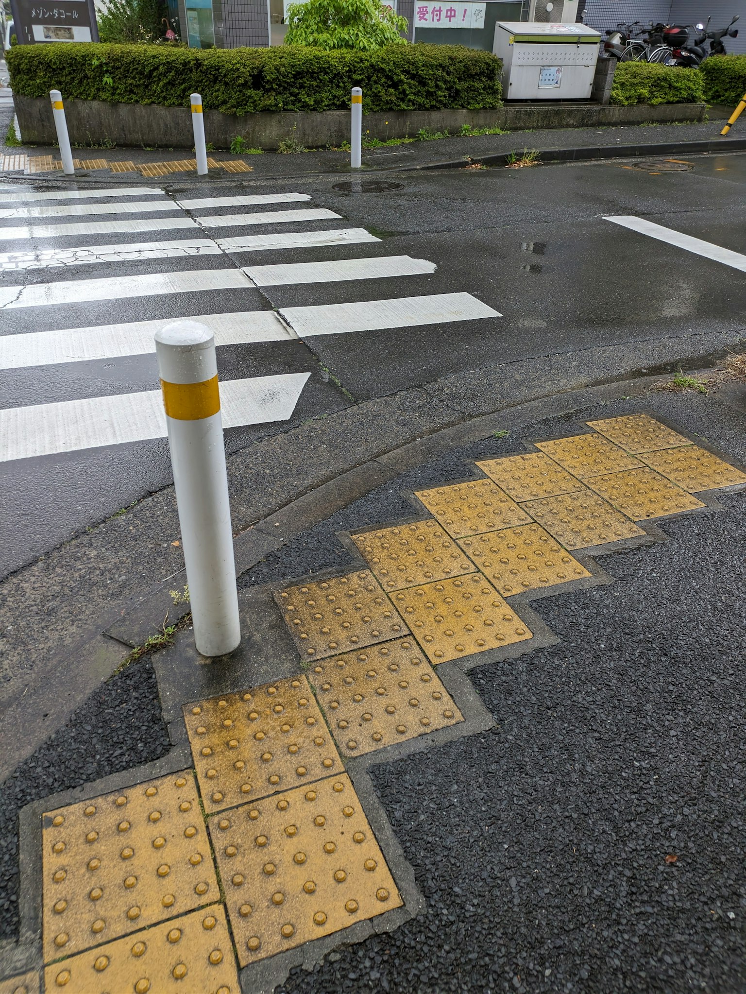 Baldosa táctil amarilla cerca de un paso de peatones con un poste blanco