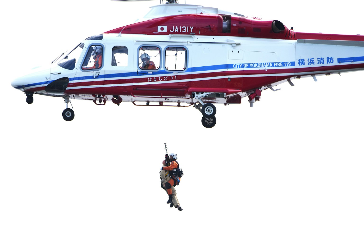 Personel penyelamat yang turun dengan tali dari helikopter merah dan putih