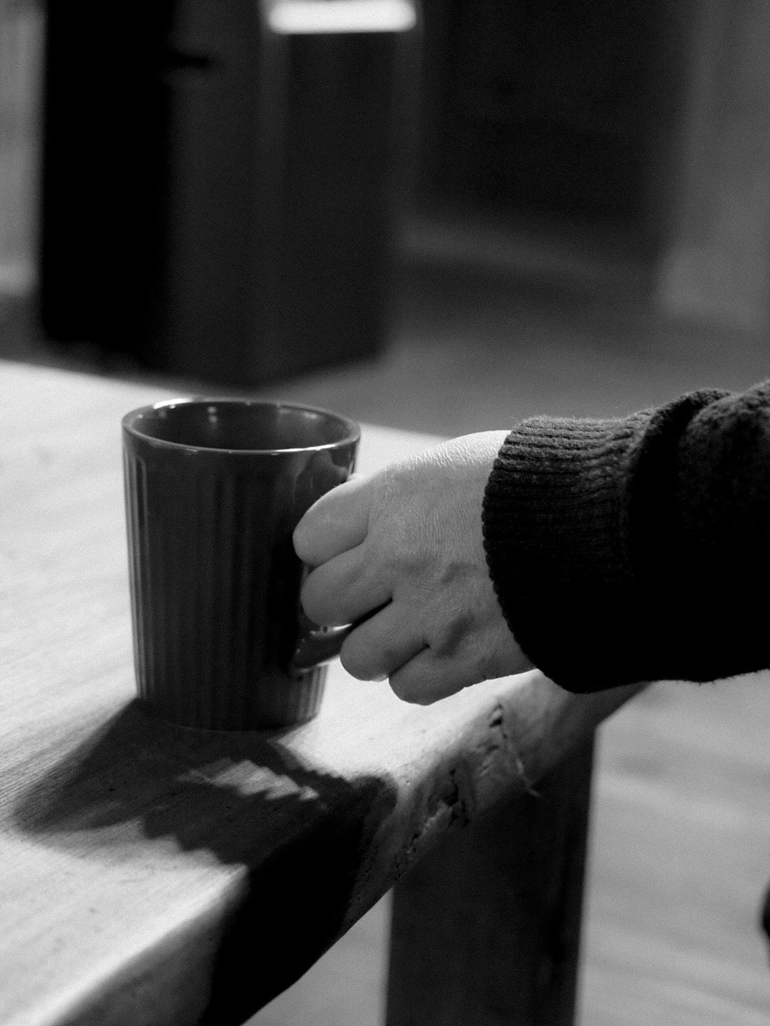 手伸向木桌上的咖啡杯