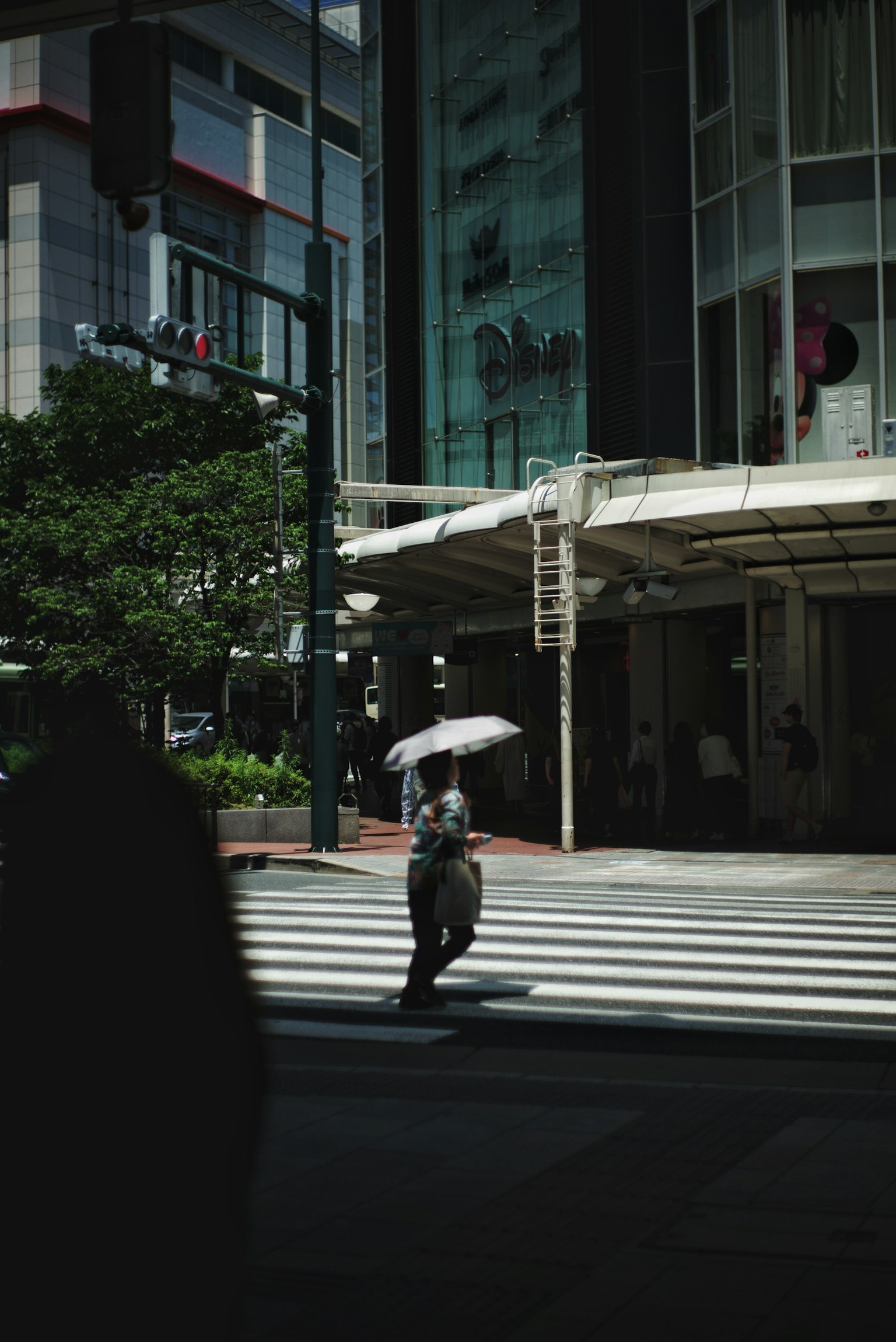 A person walking across a crosswalk with an umbrella in front of a building