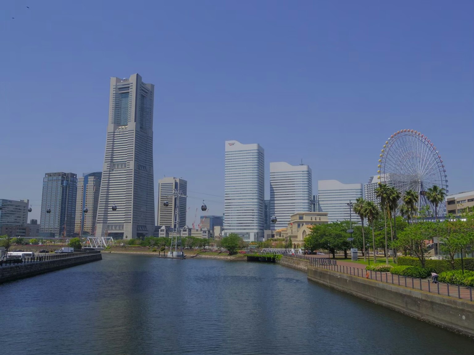 Pemandangan garis langit Yokohama dengan gedung pencakar langit dan roda ferris di bawah langit biru yang cerah