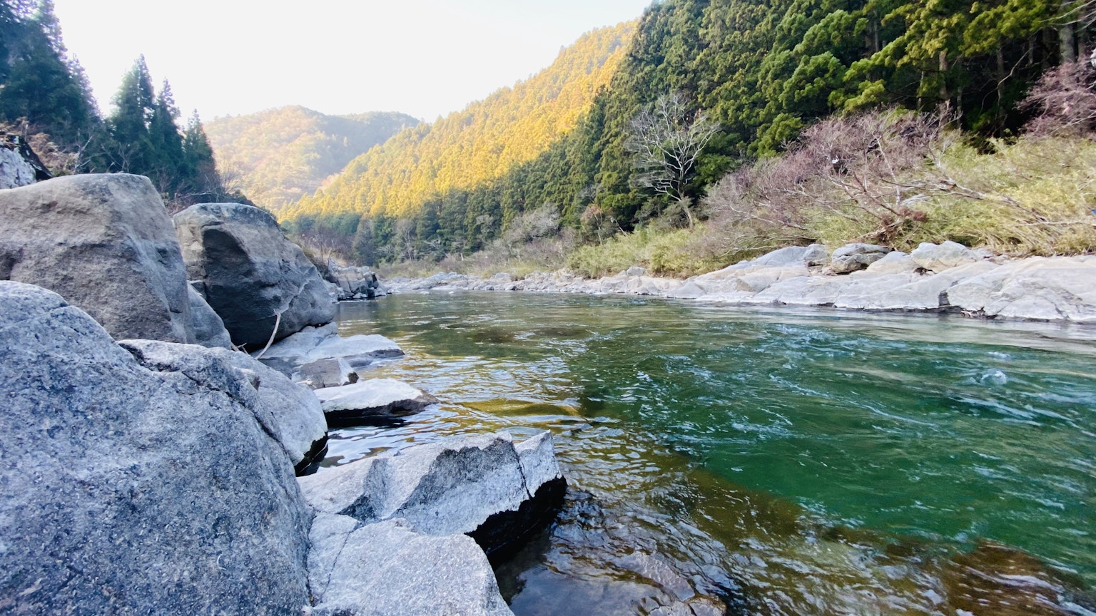 Scenic river with clear water and rocky banks surrounded by lush mountains