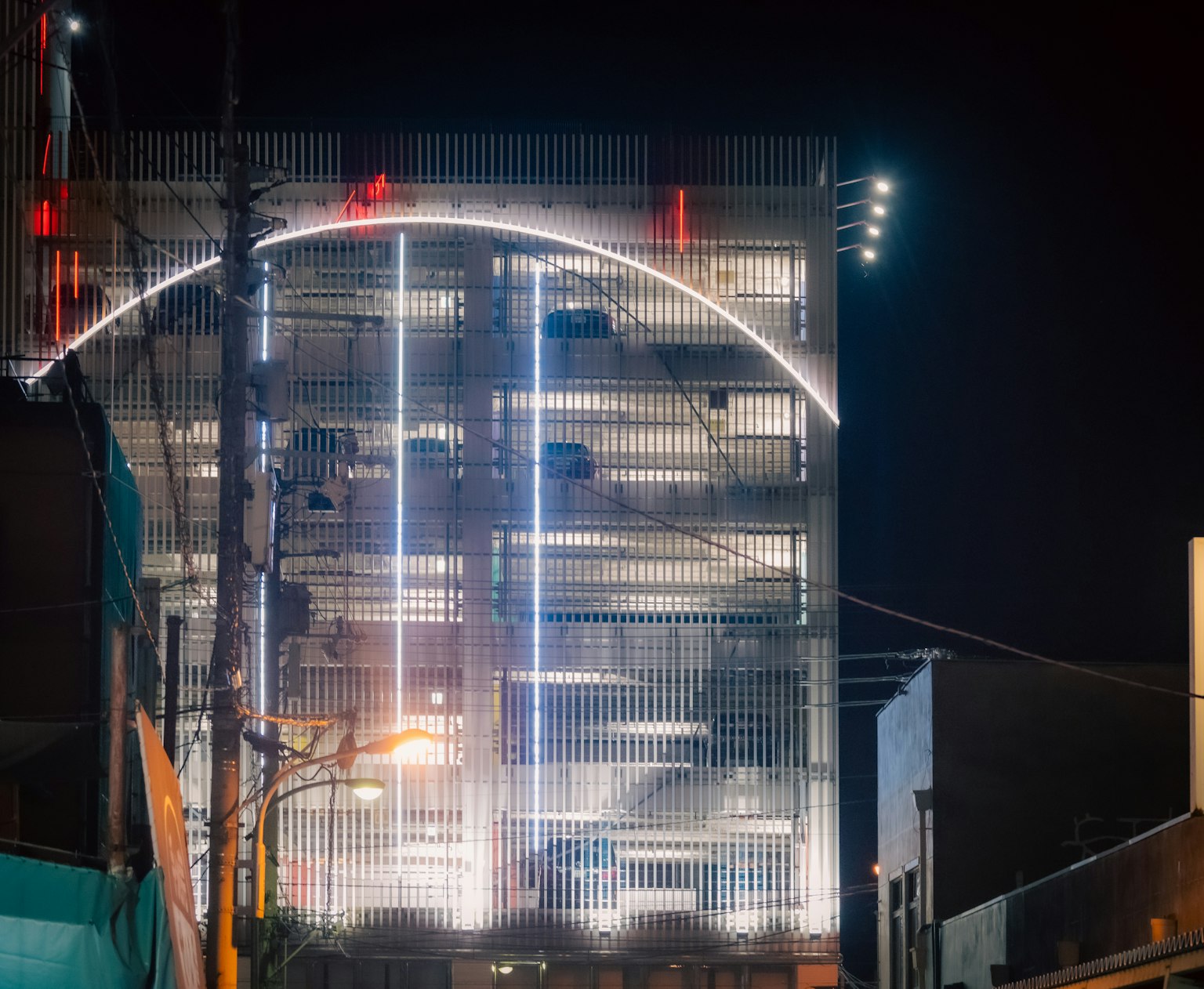 Moderner Parkhaus bei Nacht beleuchtet mit einem auffälligen Lichtbogen
