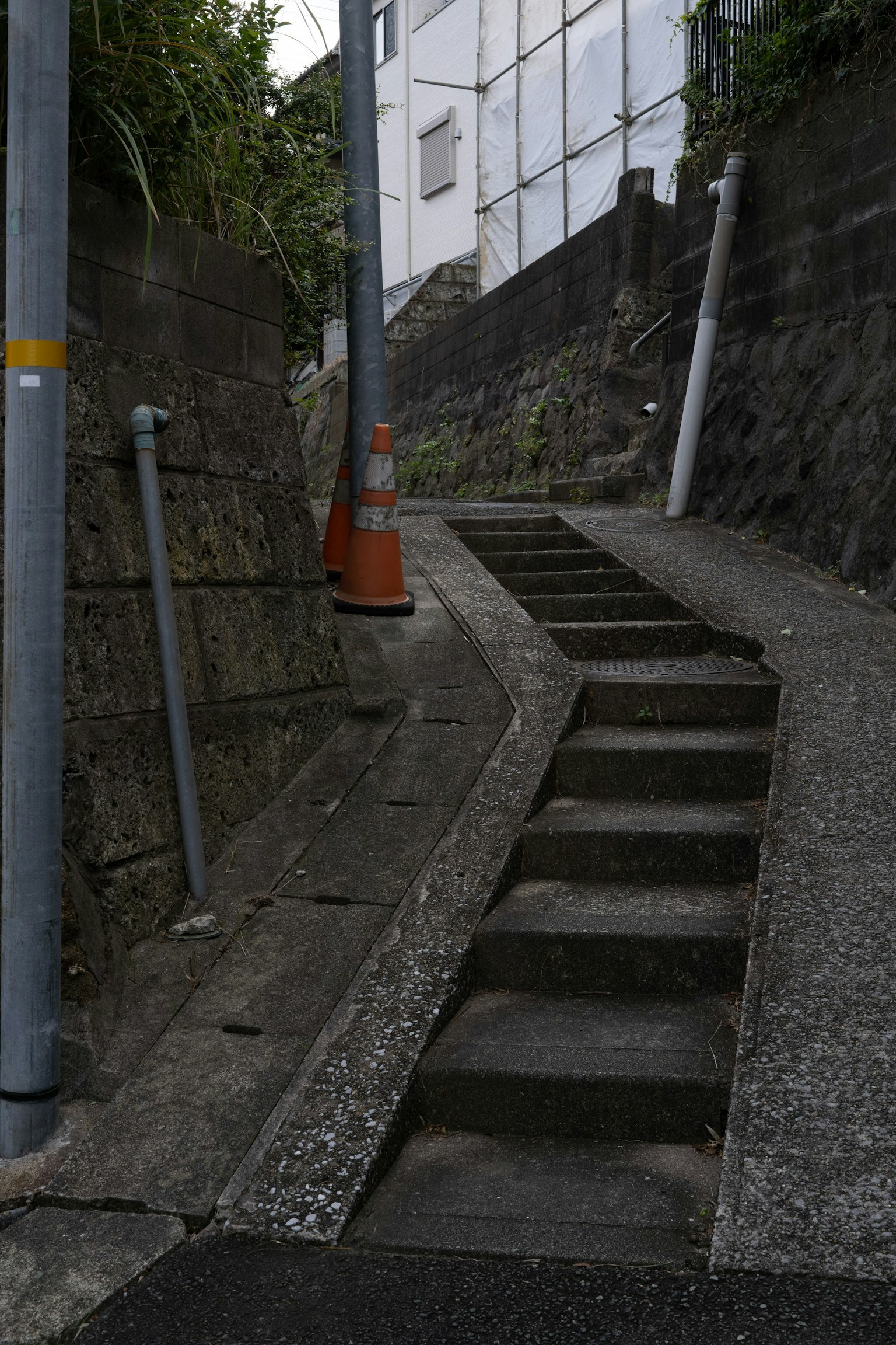 Narrow winding staircase with concrete walls and street poles