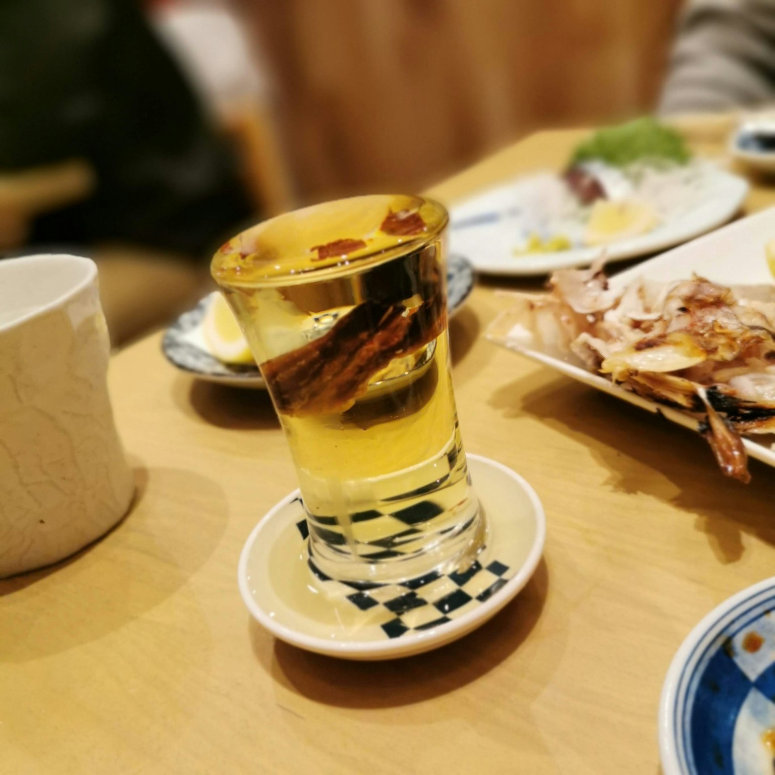 테이블 위에 음식 접시 옆에 있는 노란 음료와 향신료가 담긴 잔