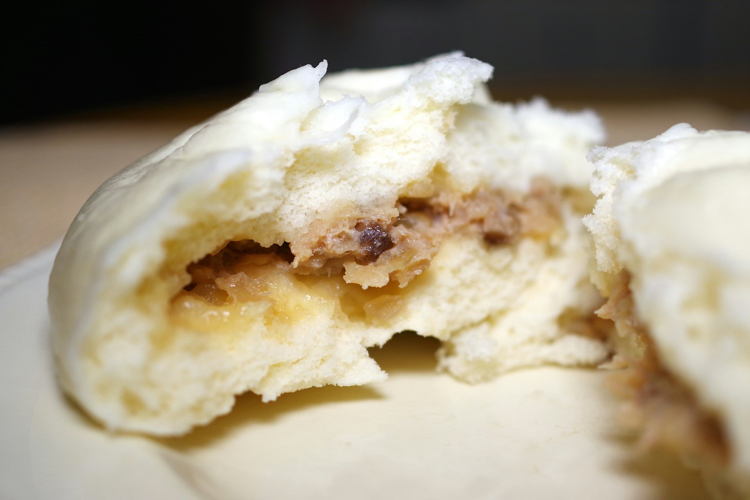 Nahaufnahme eines fluffigen weißen Dampfbuns mit süßer Füllung innen
