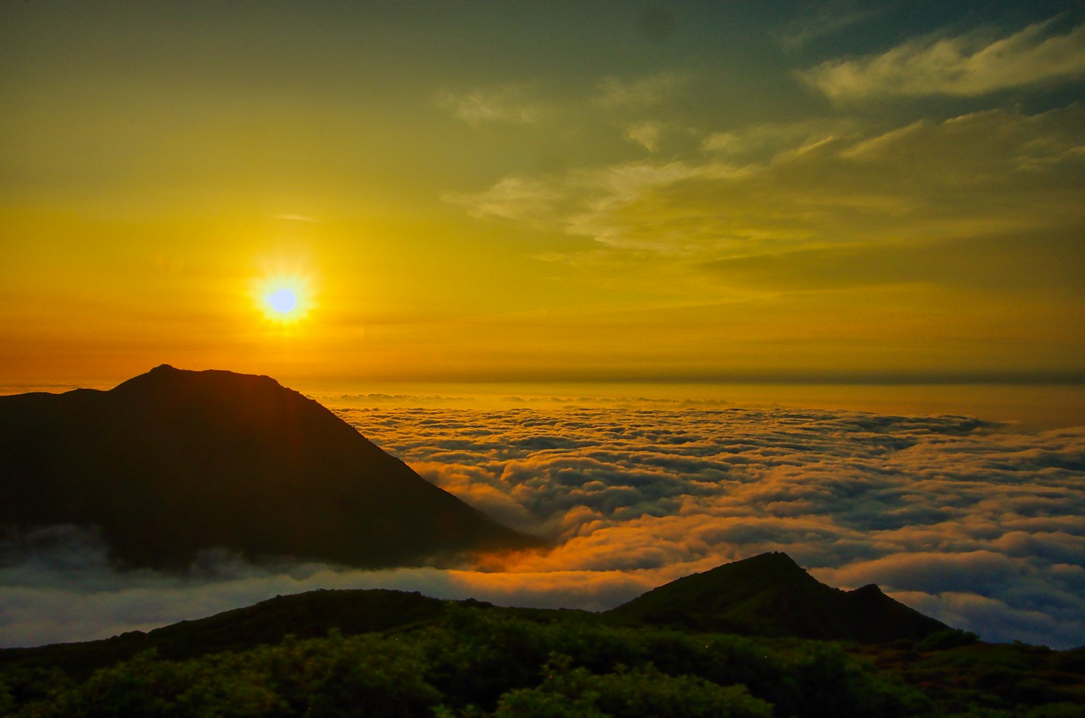 Stupendo paesaggio di nuvole sotto le montagne con un sole che sorge