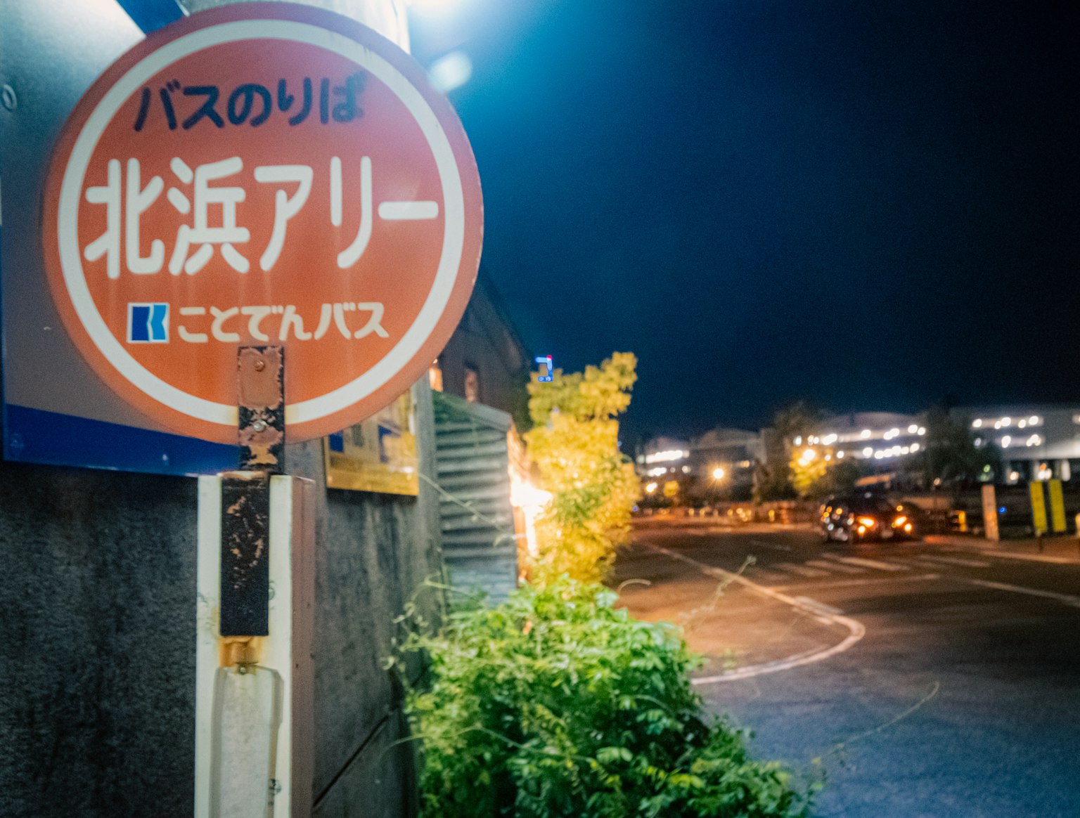夜間的北濱小巷公車站標誌 周圍有綠植和路燈