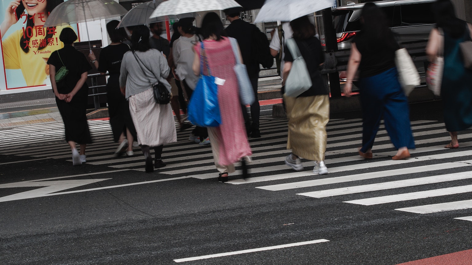 Des personnes avec des parapluies traversant un passage piéton