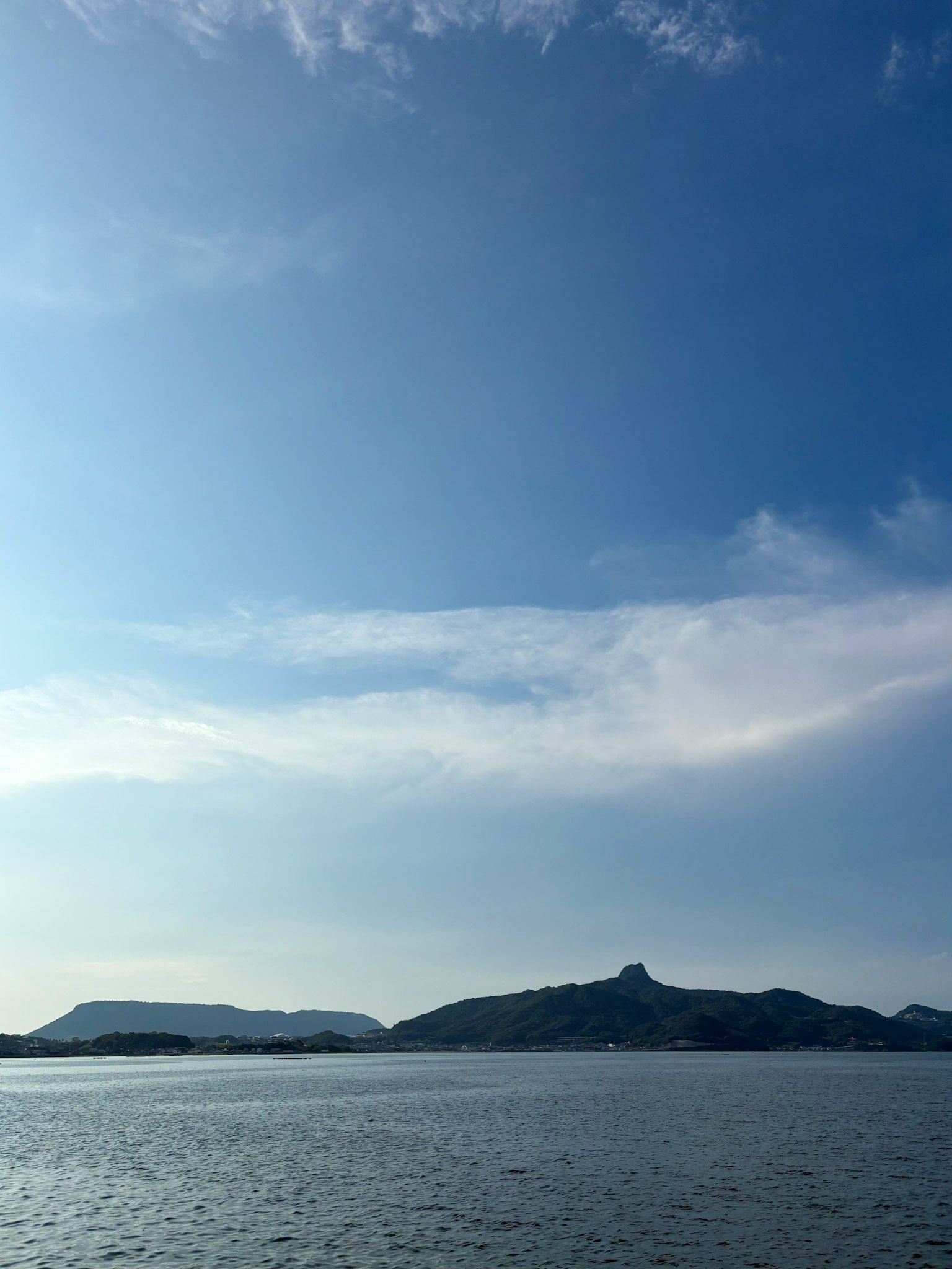 青い空と穏やかな海の風景 遠くに山が見える