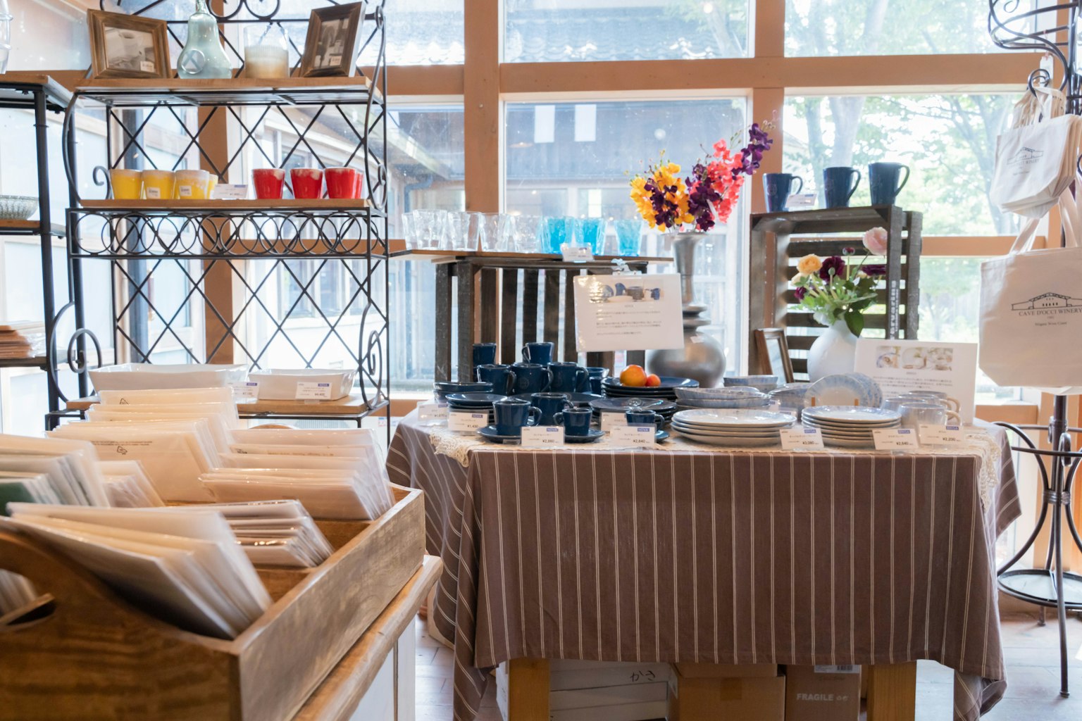 Interior de tienda brillante con una mesa de exhibición que contiene vajilla y un jarrón