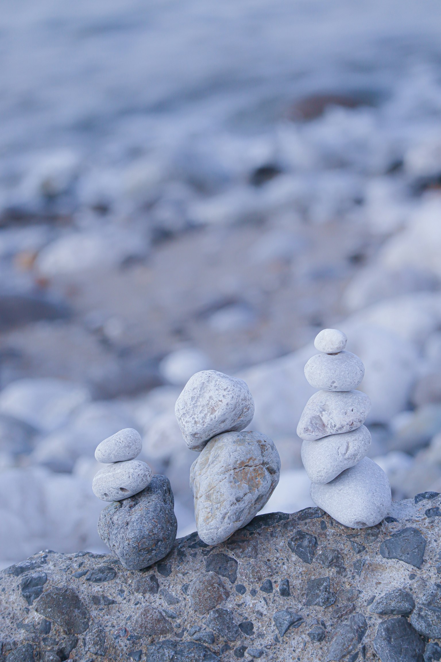 Small sculptures of stacked white stones against a blue background