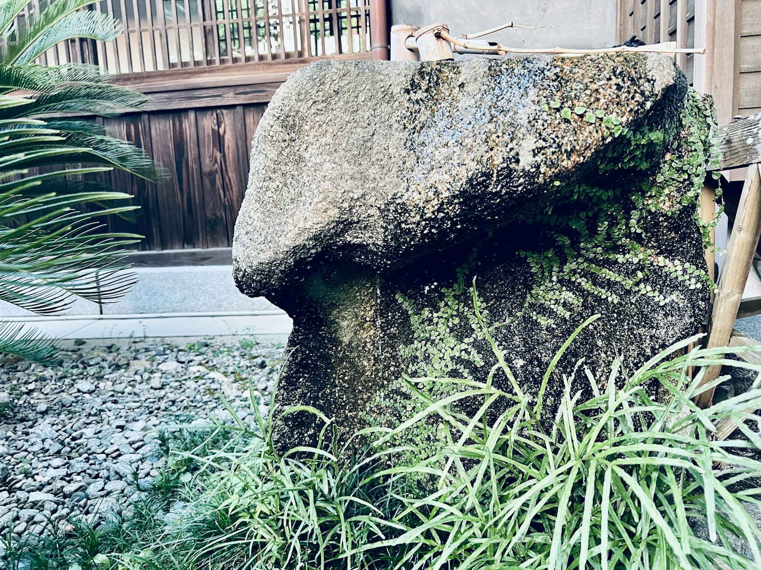 Escultura de piedra en un jardín rodeado de plantas verdes