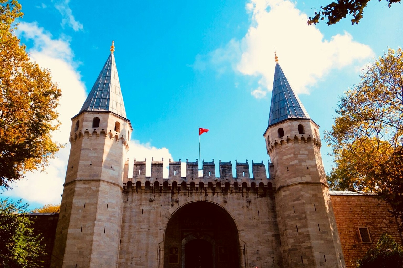 Entrada de un castillo histórico con dos torres puntiagudas bajo un cielo azul