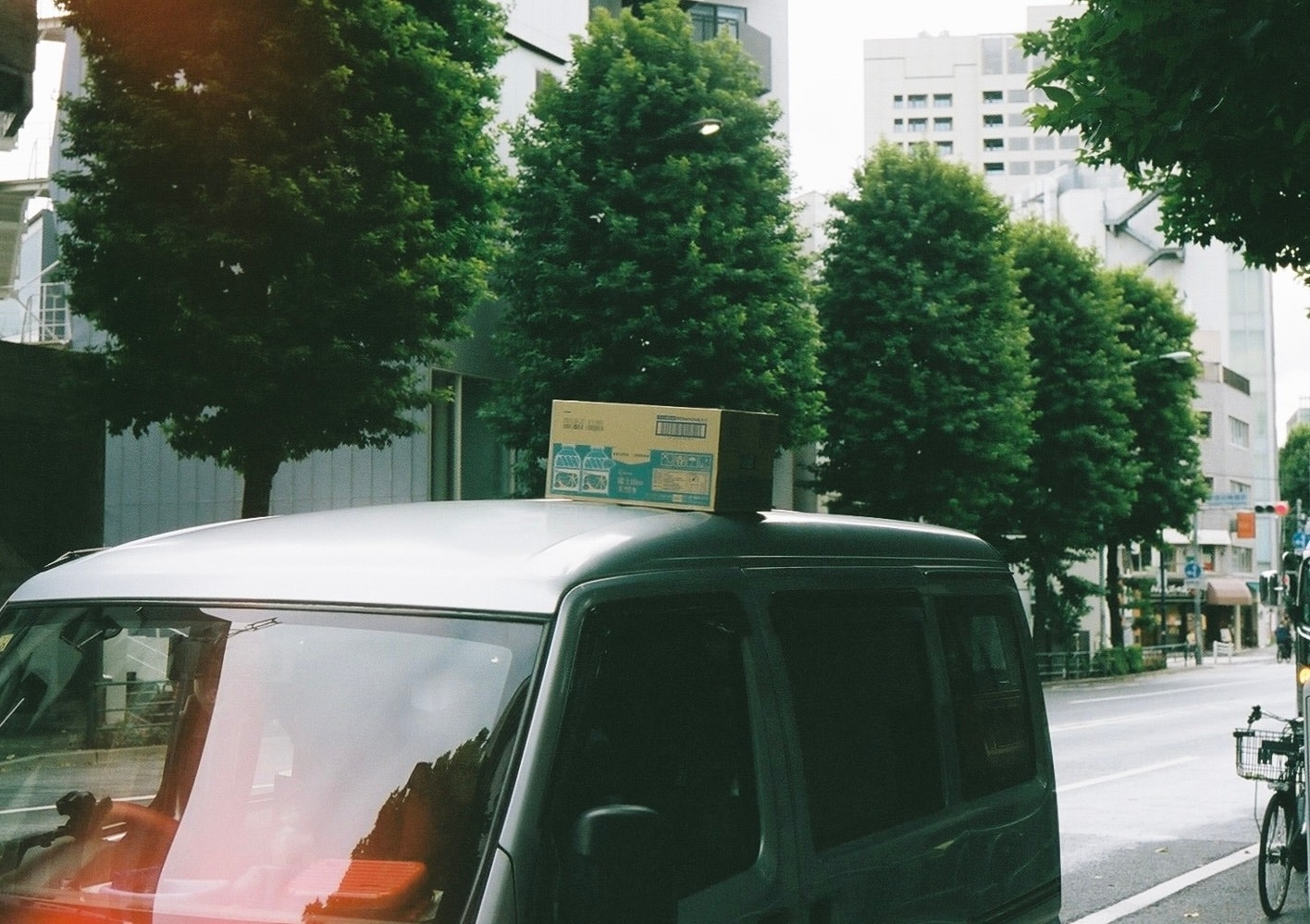 街路樹の並ぶ道路を走る黒い車のフロント