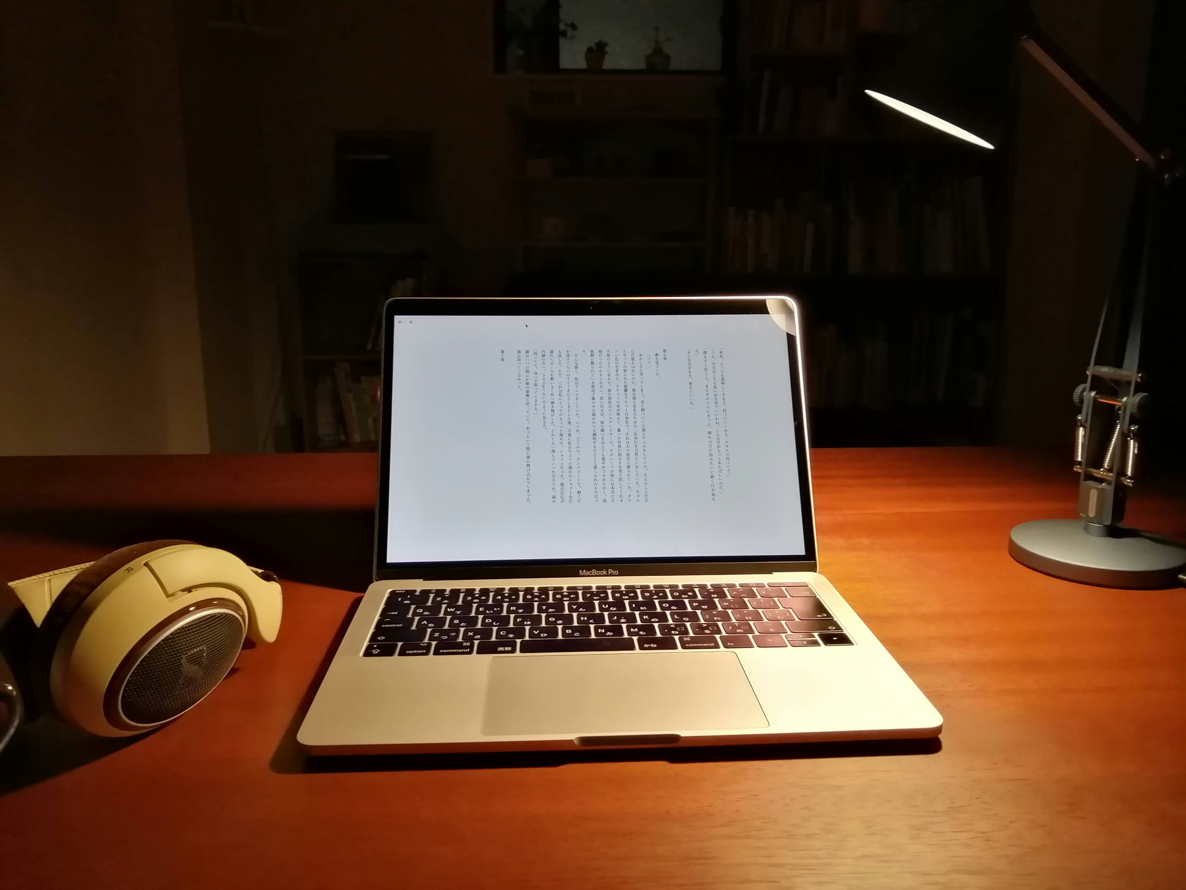 Computer portatile su una scrivania con cuffie e lampada da scrivania regolabile