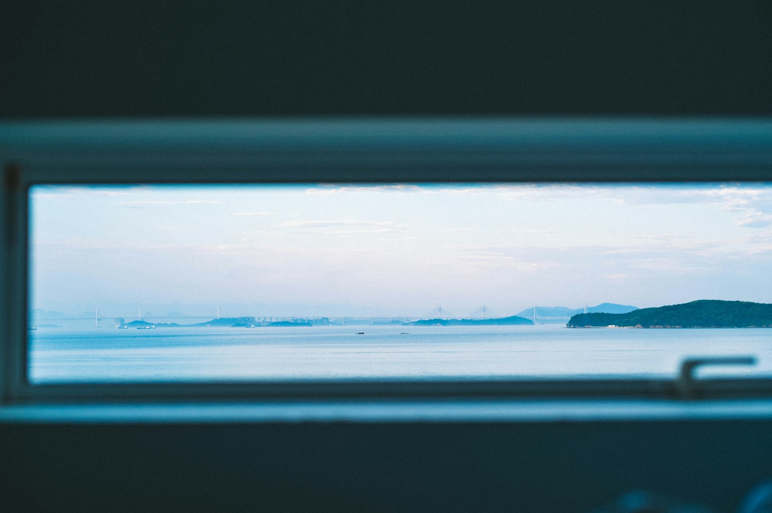 Blick auf das ruhige blaue Meer und den Himmel durch ein Fenster