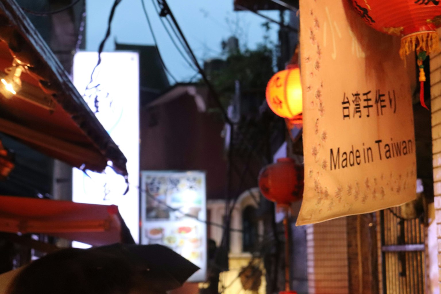 黃昏時分的街道場景，紅色燈籠和寫有台灣製造的招牌