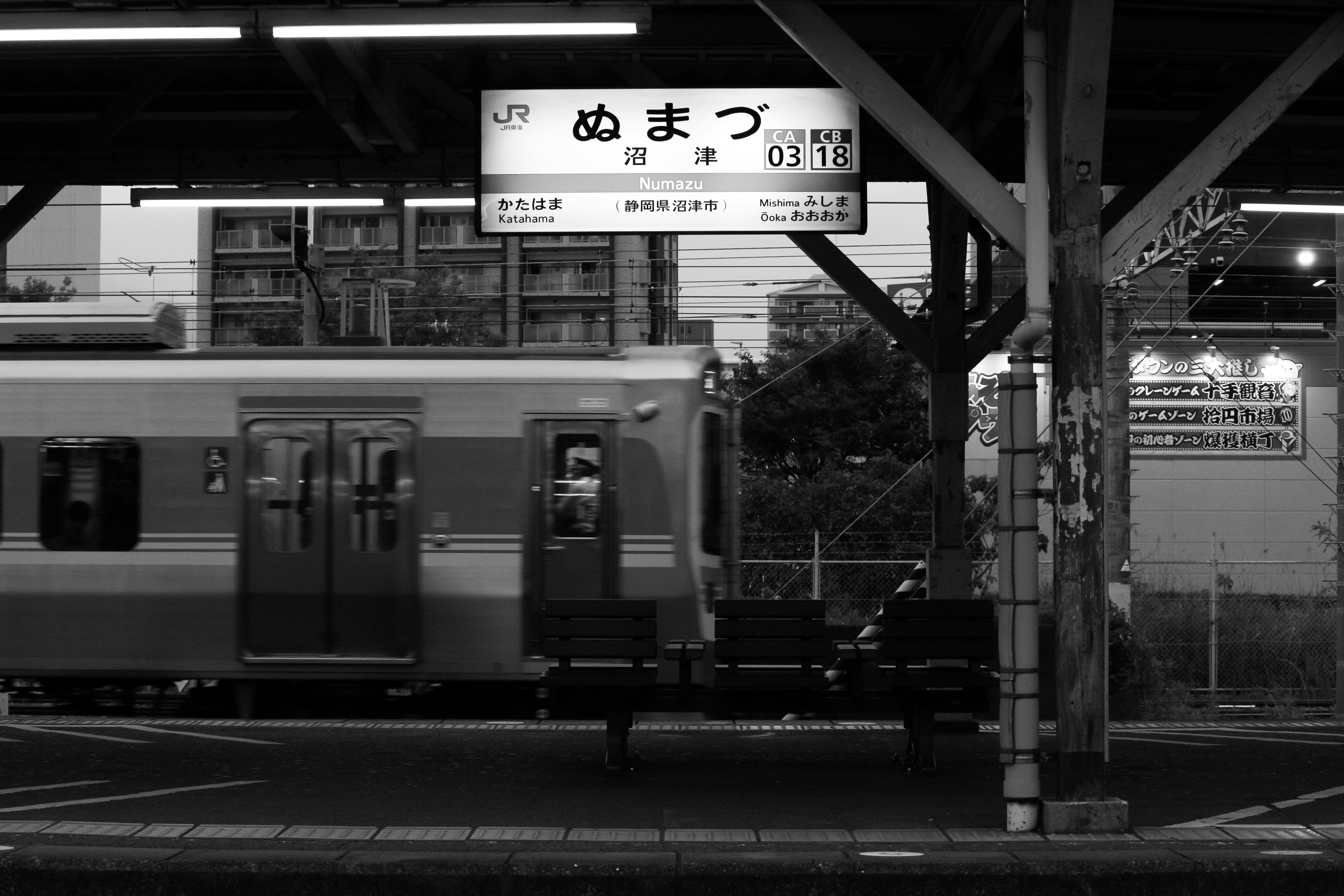 駅のホームを走る電車と停車中の車両のある風景
