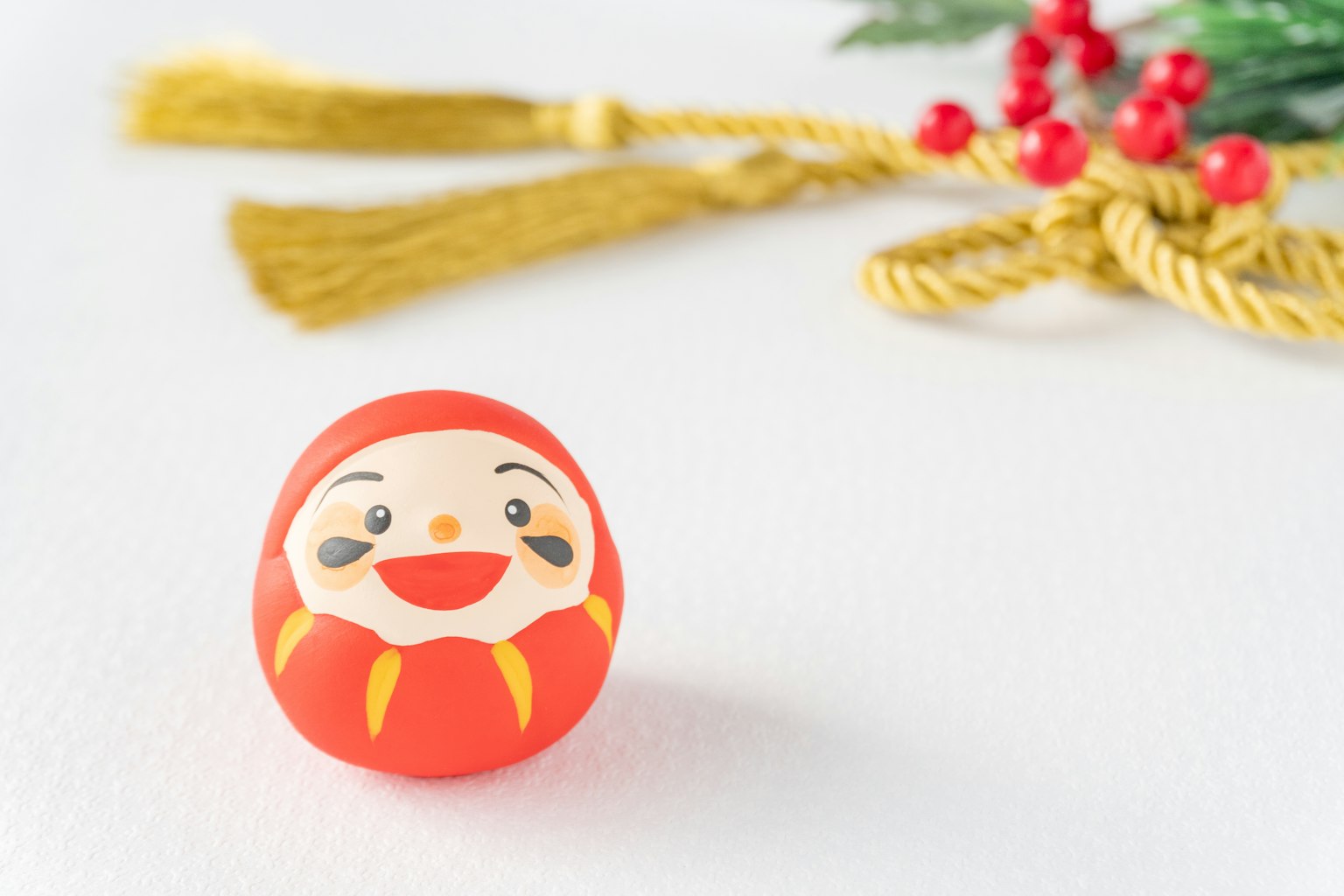 Rote Daruma-Puppe mit lächelndem Gesicht vor goldener Dekoration