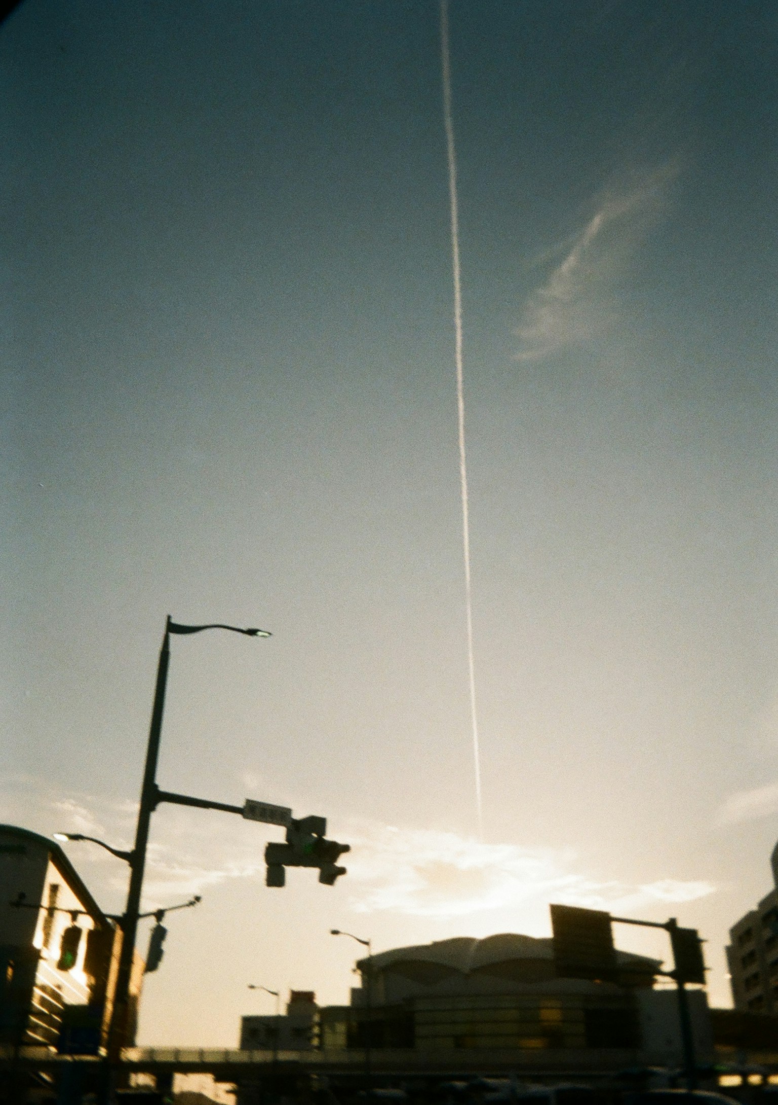 Kondensstreifen, der sich über den Himmel erstreckt, mit städtischen Silhouetten
