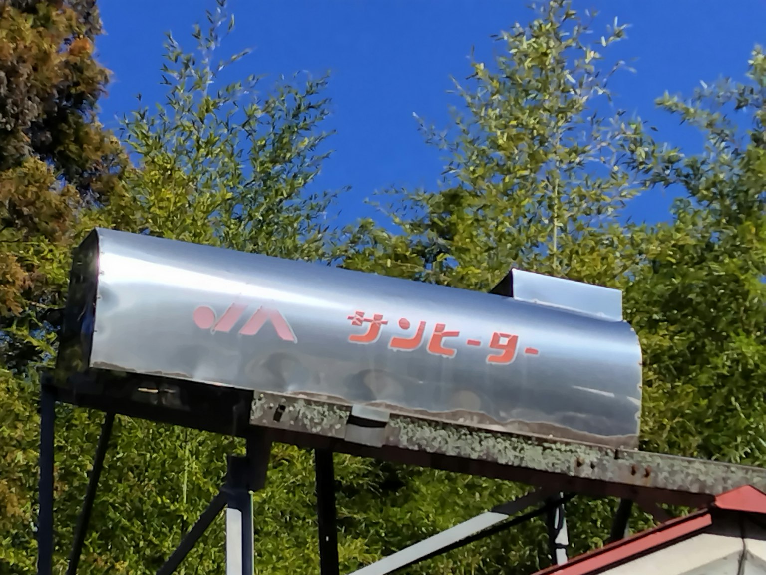 Metallschild mit dem Wort 'Sonnenheizung' in roten Buchstaben vor einem klaren blauen Himmel