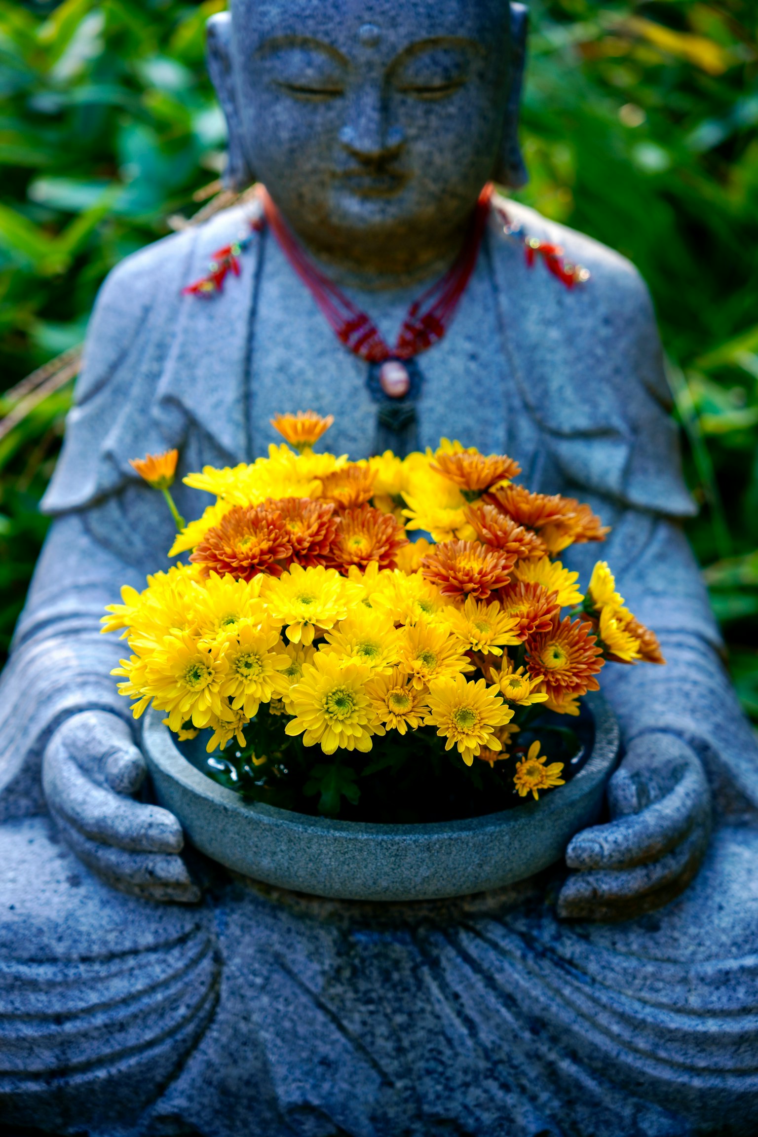 Statue du Bouddha tenant un bol de fleurs jaunes