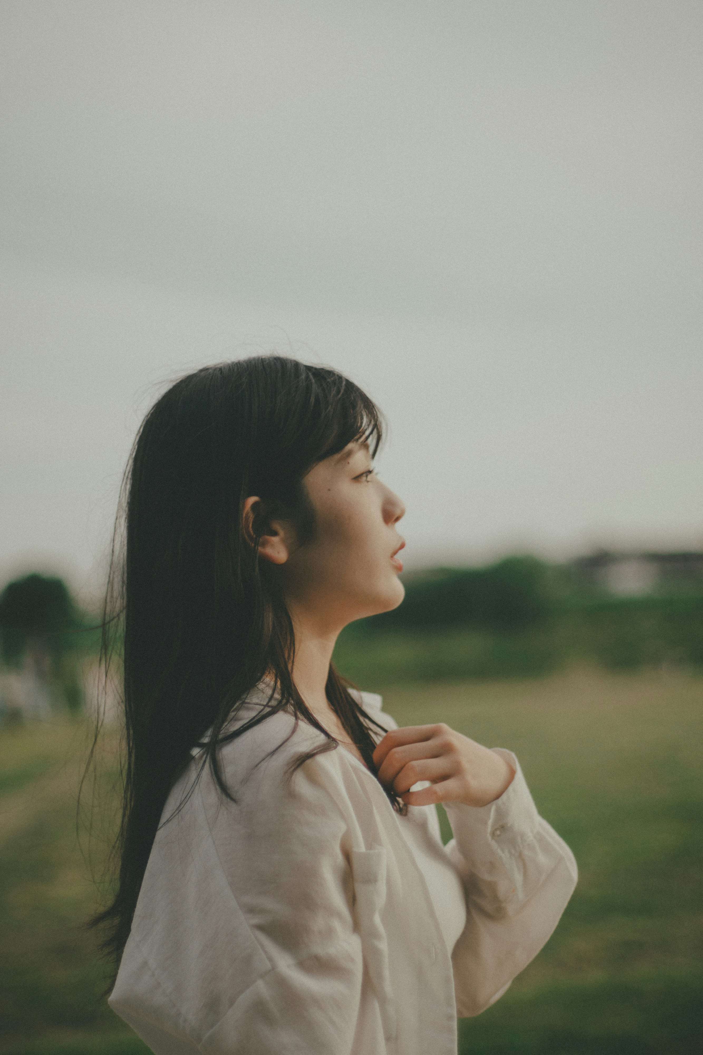 草原を背景に横顔で微笑む女性の肖像