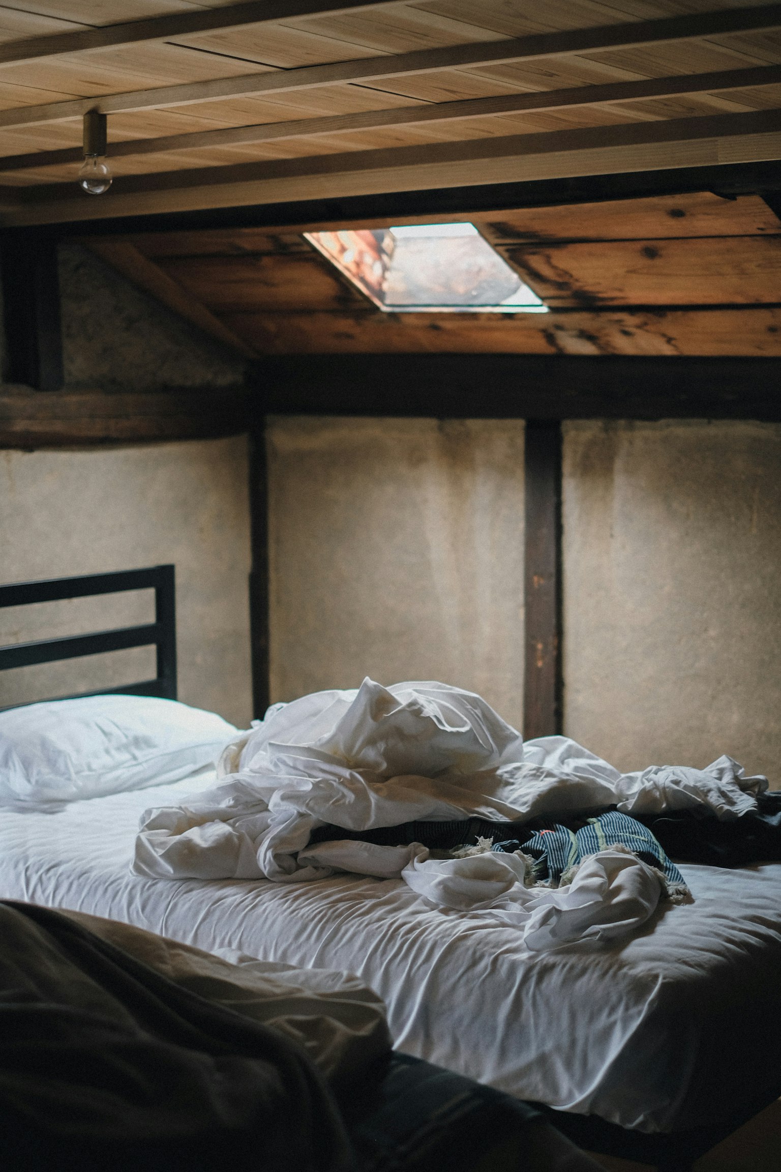 Un intérieur de chambre simple avec des draps et des couvertures blanches froissés éparpillés sur le lit