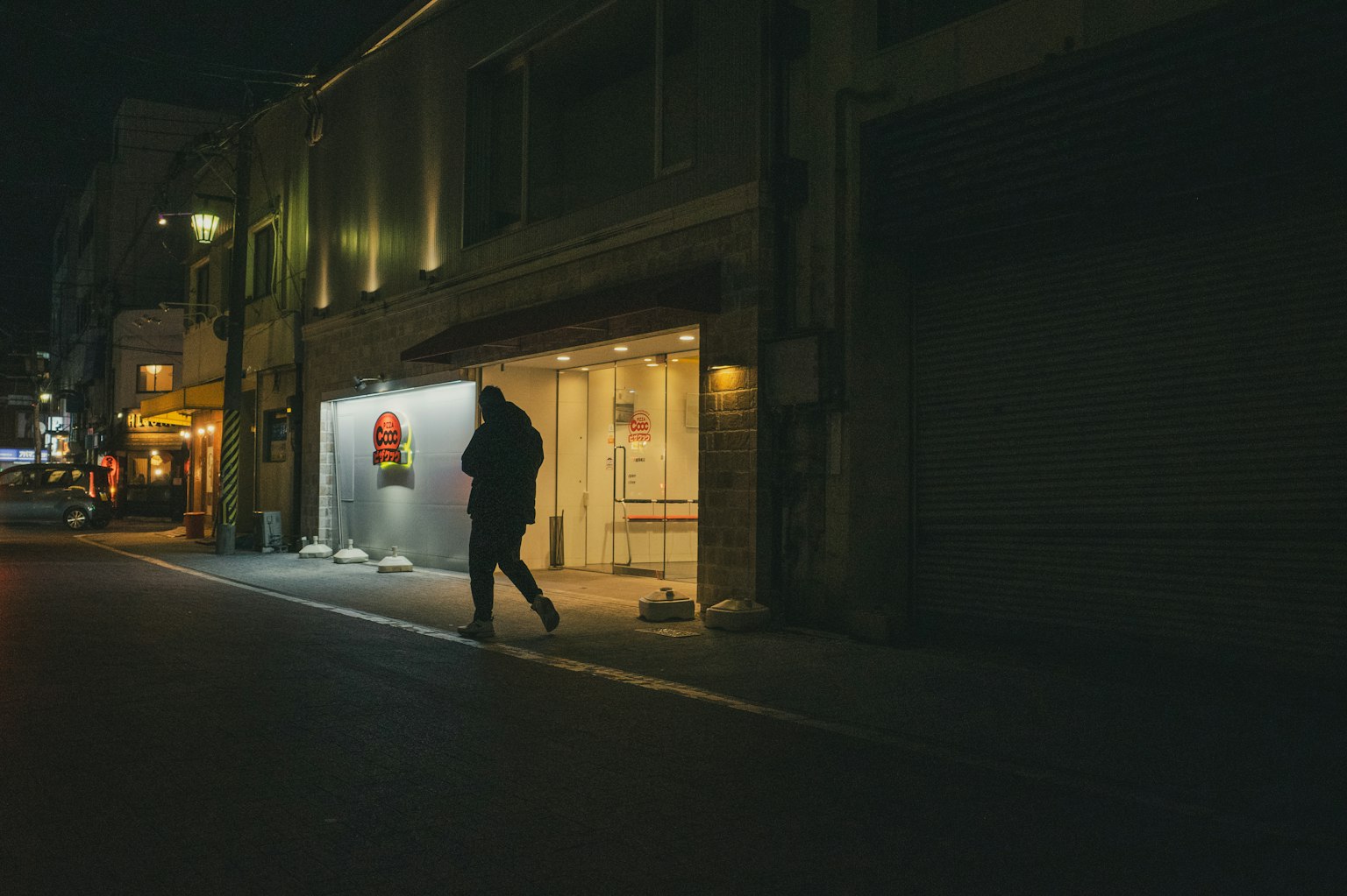 Una persona che cammina in una strada notturna con un'insegna luminosa