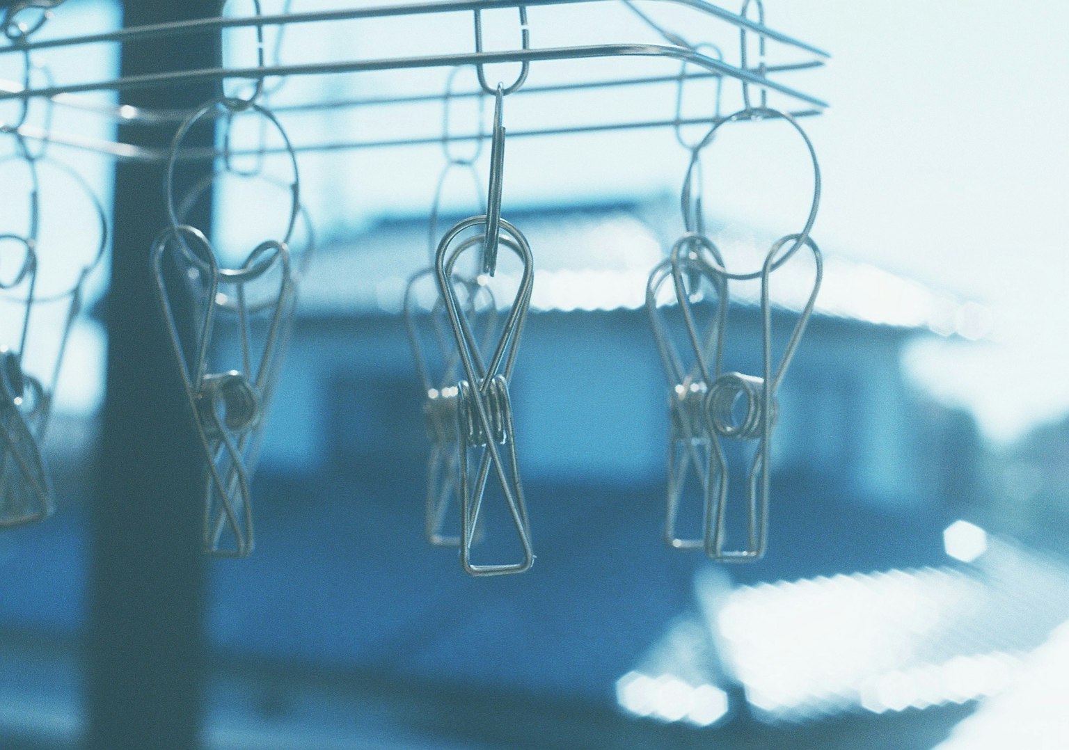 Metal clothespins hanging against a blue background