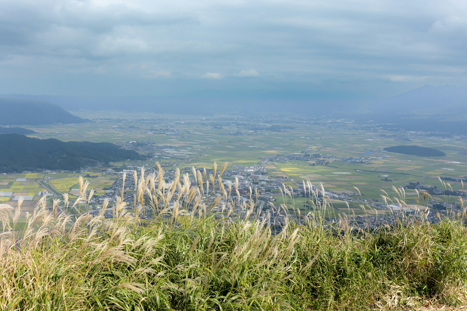 Pemandangan indah dari puncak gunung dengan rumput subur dan ladang jauh