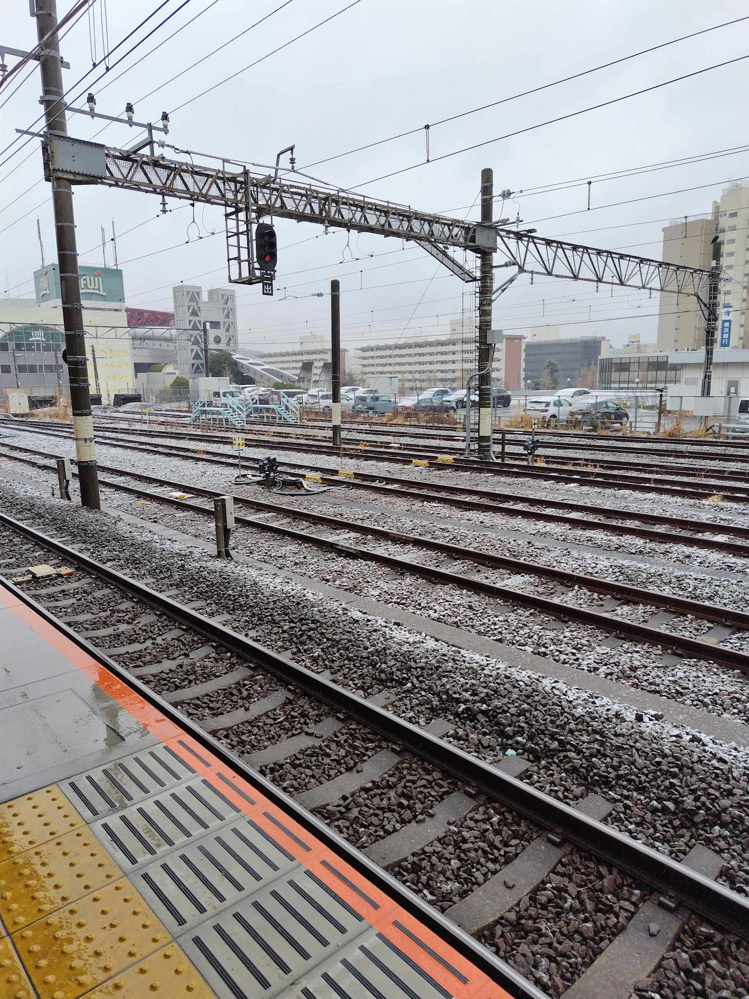 Platform stasiun kereta dengan rel di bawah hujan