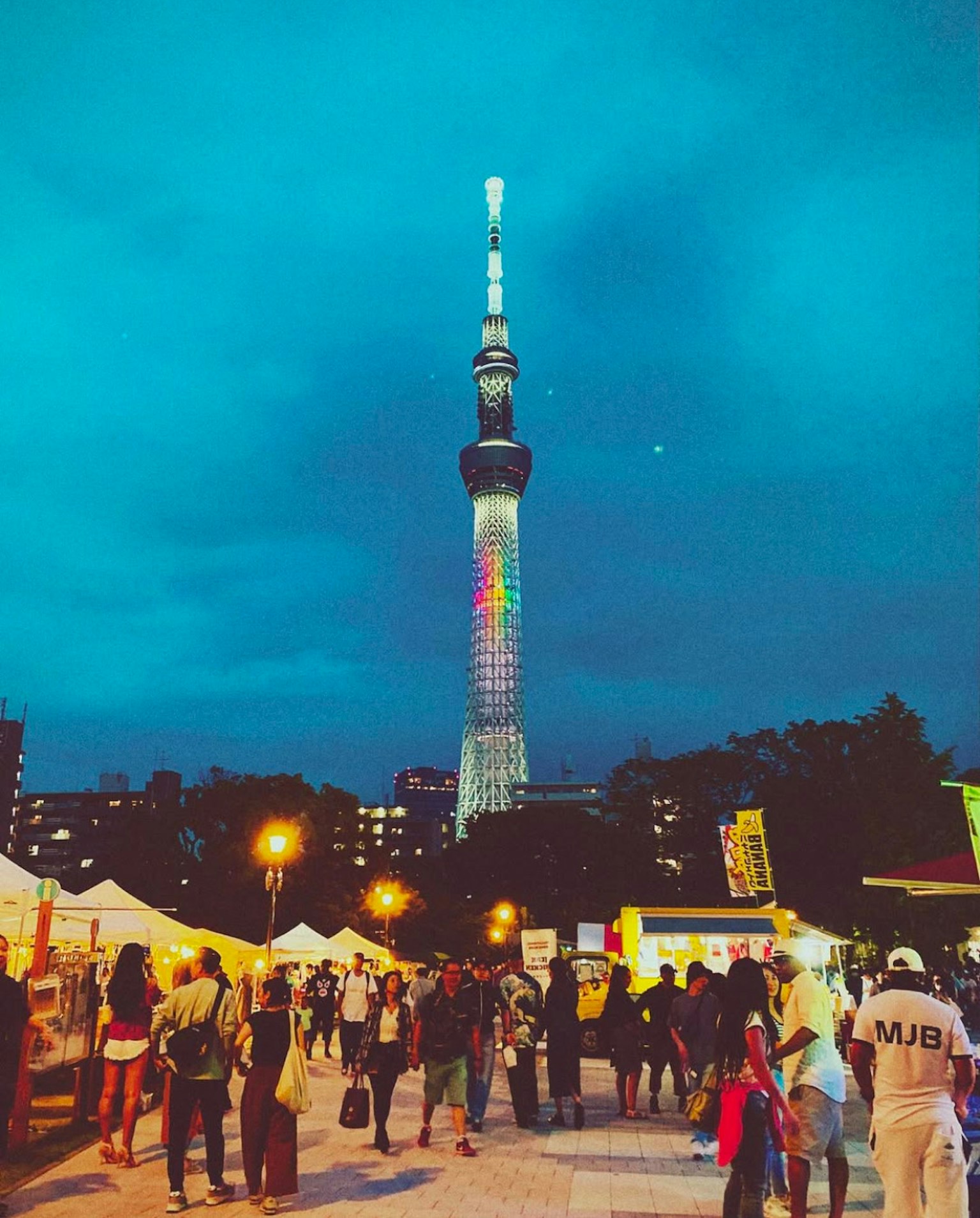 夜間照亮的東京晴空塔與熙熙攘攘的人群和節日帳篷