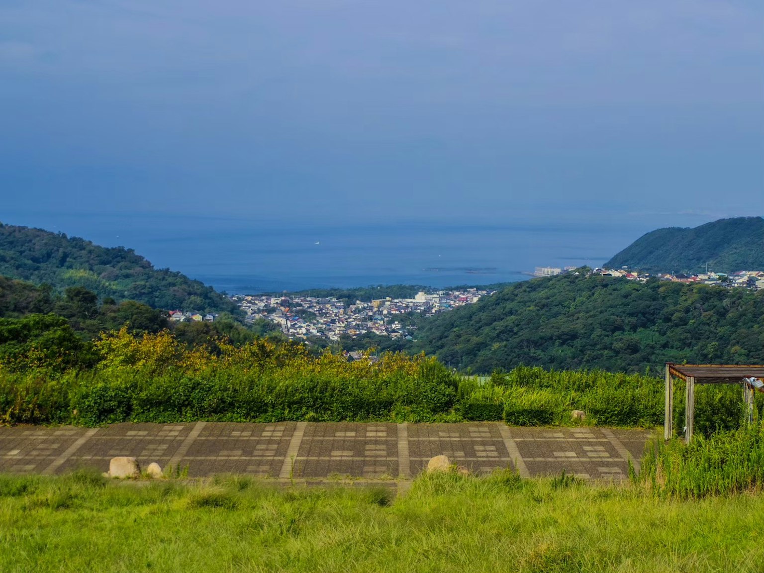 Pemandangan indah desa tenang dengan laut biru dan bukit hijau di latar belakang